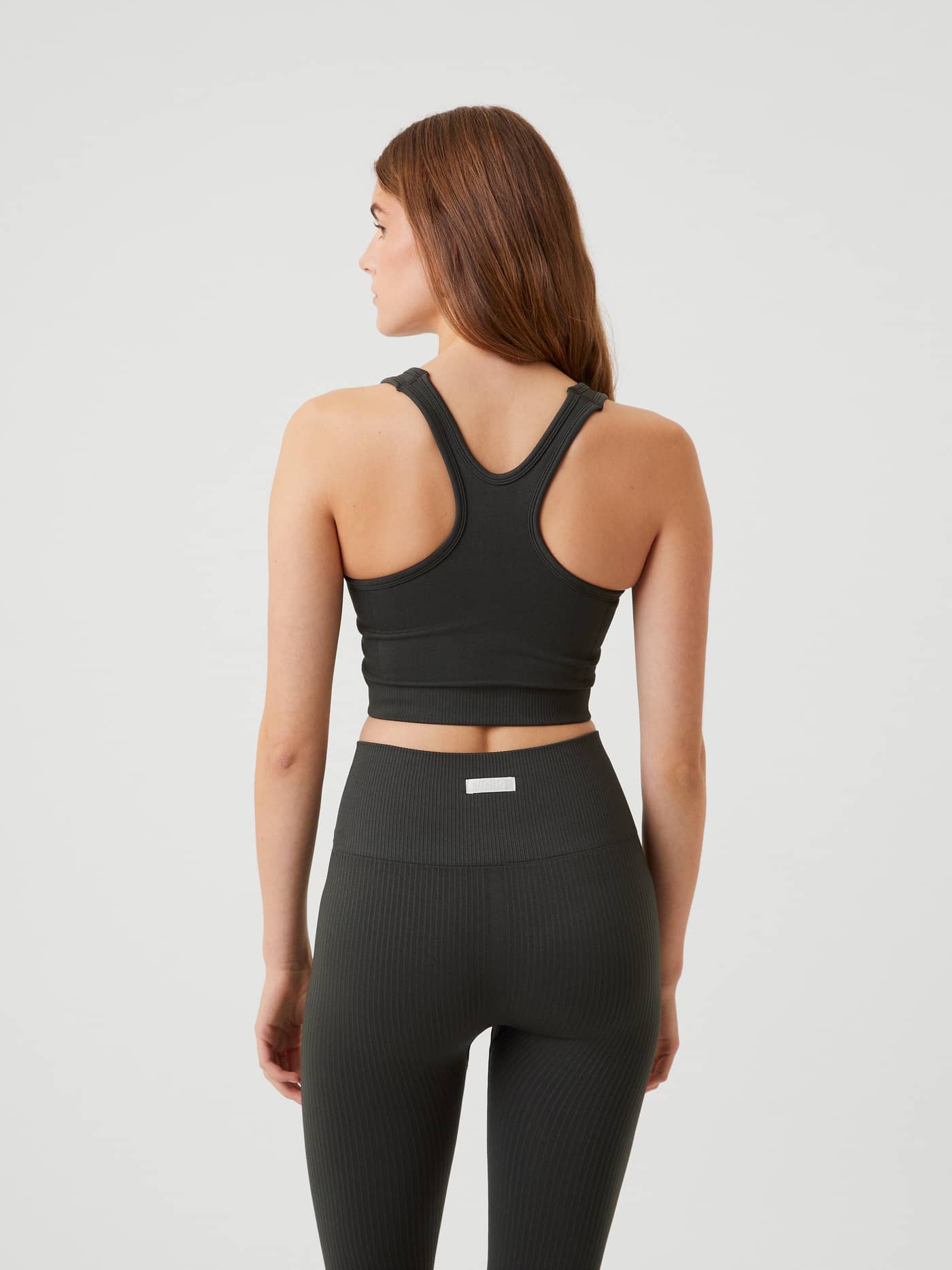 Back view of a model wearing the ribbed Björn Borg Studio Low  Seamless Bra in Peat (Green) for training. - Image 4
