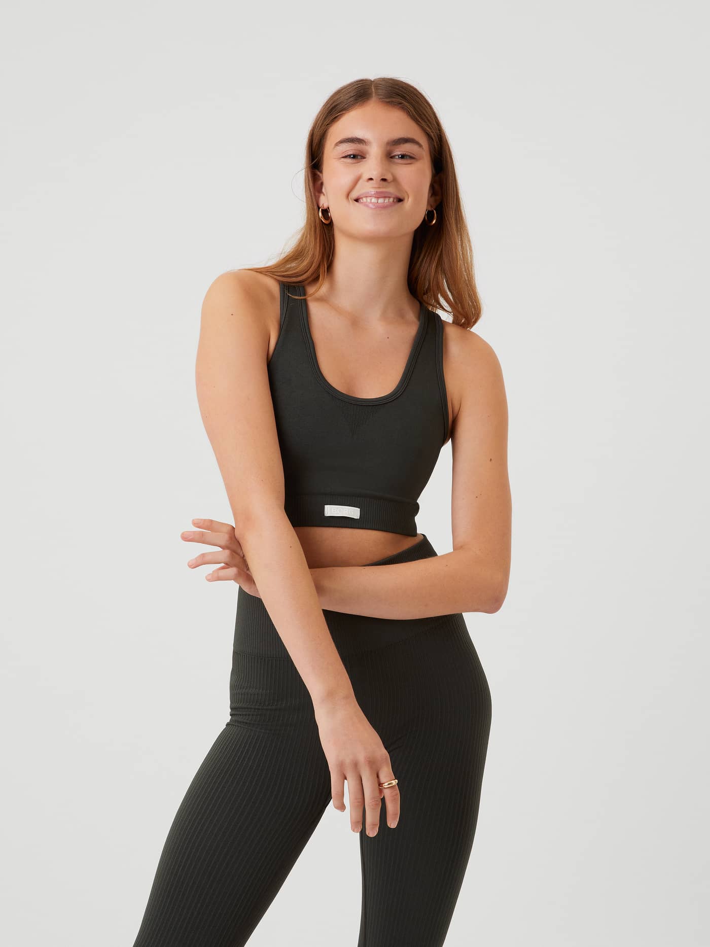 Front view of a model wearing the ribbed Studio Low Seamless Bra in Peat (Green) with a white logo for training. - Image 3