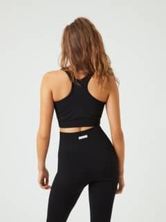 Vue de dos d'une femme portant la Studio Low Seamless Bra noire avec dos nageur offrant un bon maintien pour l'entraînement. - Image 3