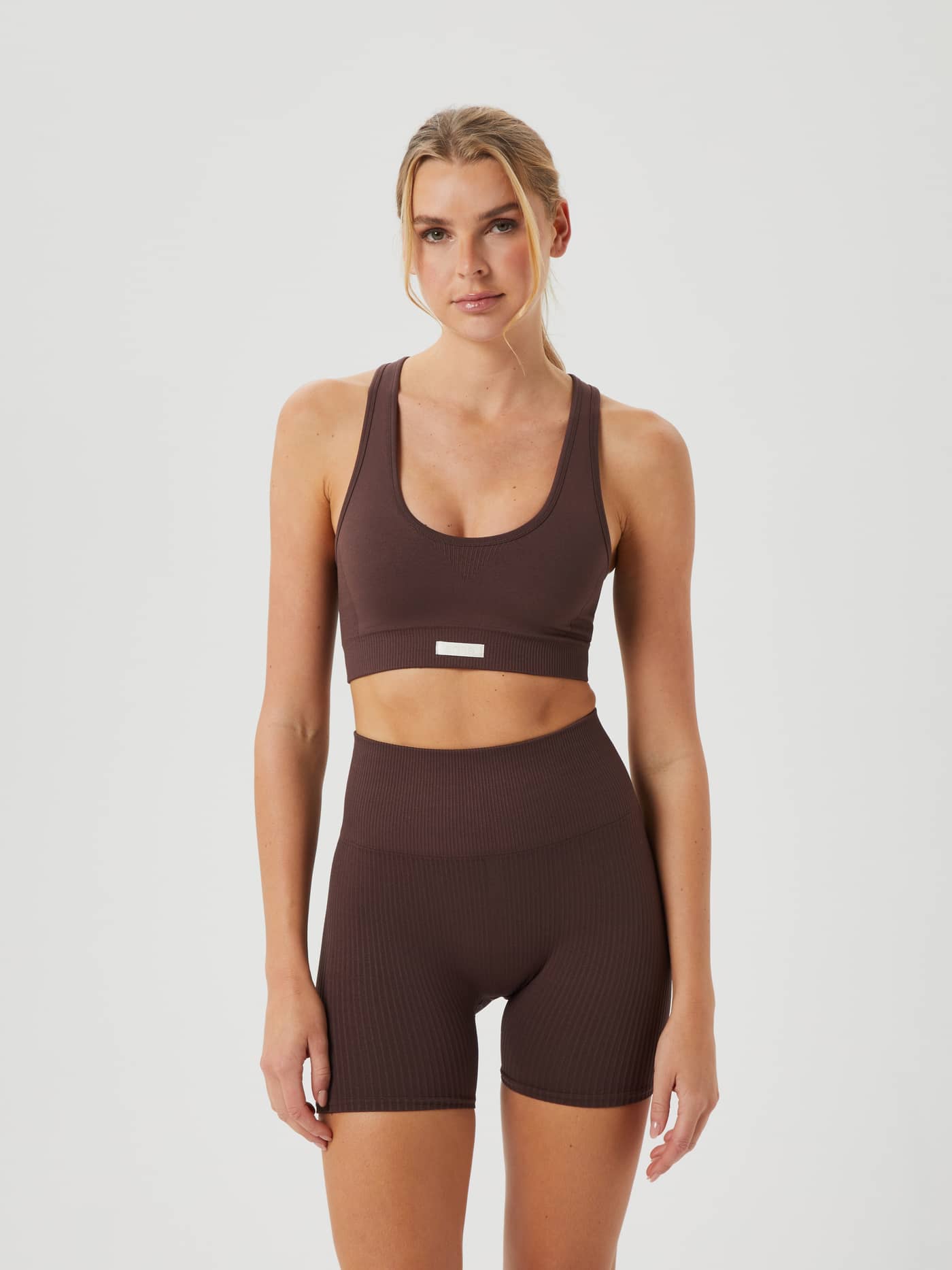 Front view of a woman wearing the brown Björn Borg Studio Low Seamless Bra, a low-support training top with a seamless fit. - Image 3