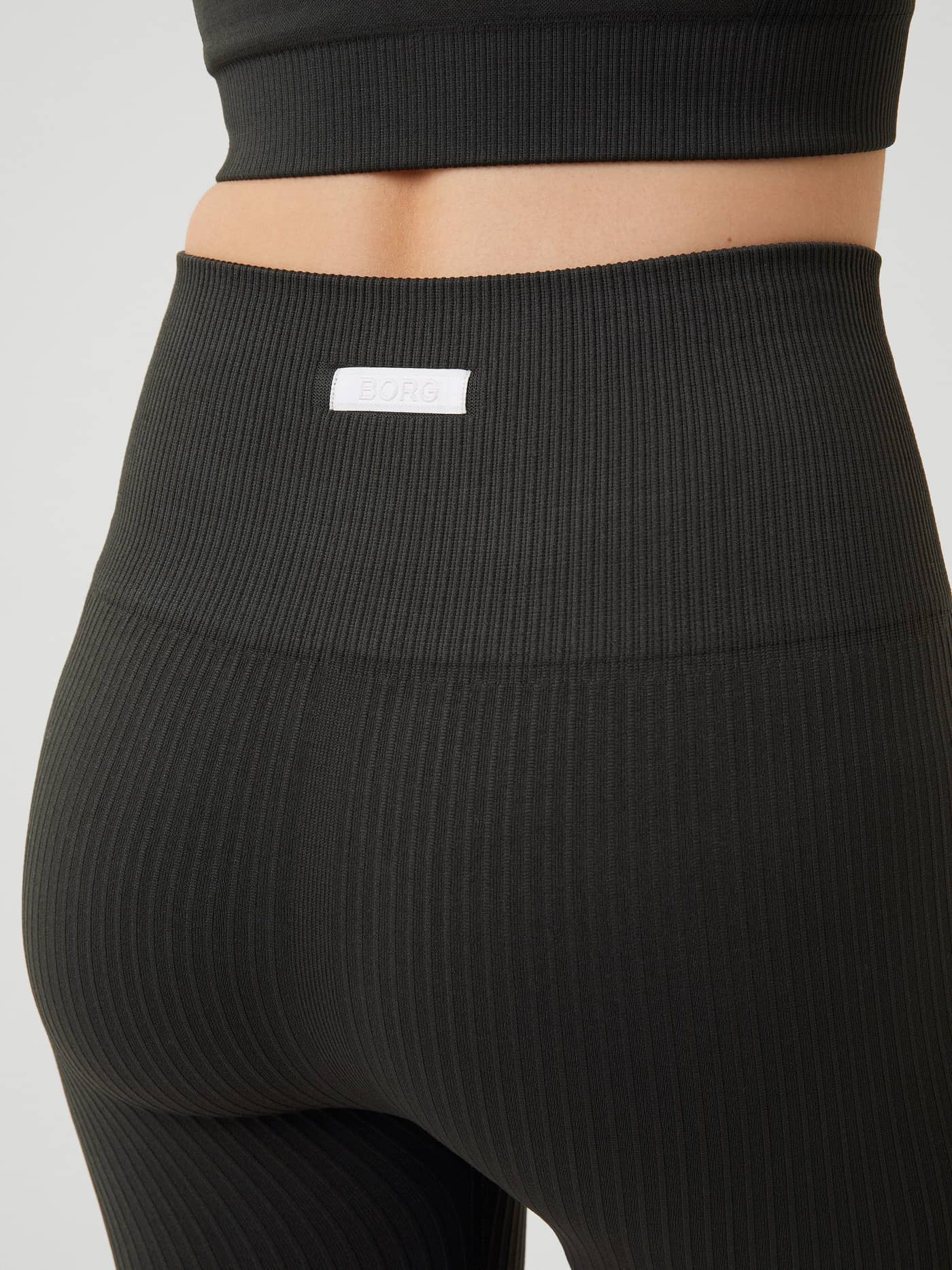 Studio Seamless Rib Shorts i Peat (Grön) sedda bakifrån i närbild med ribbstickad träningspassform och vit BORG-logotyp. - Image 4