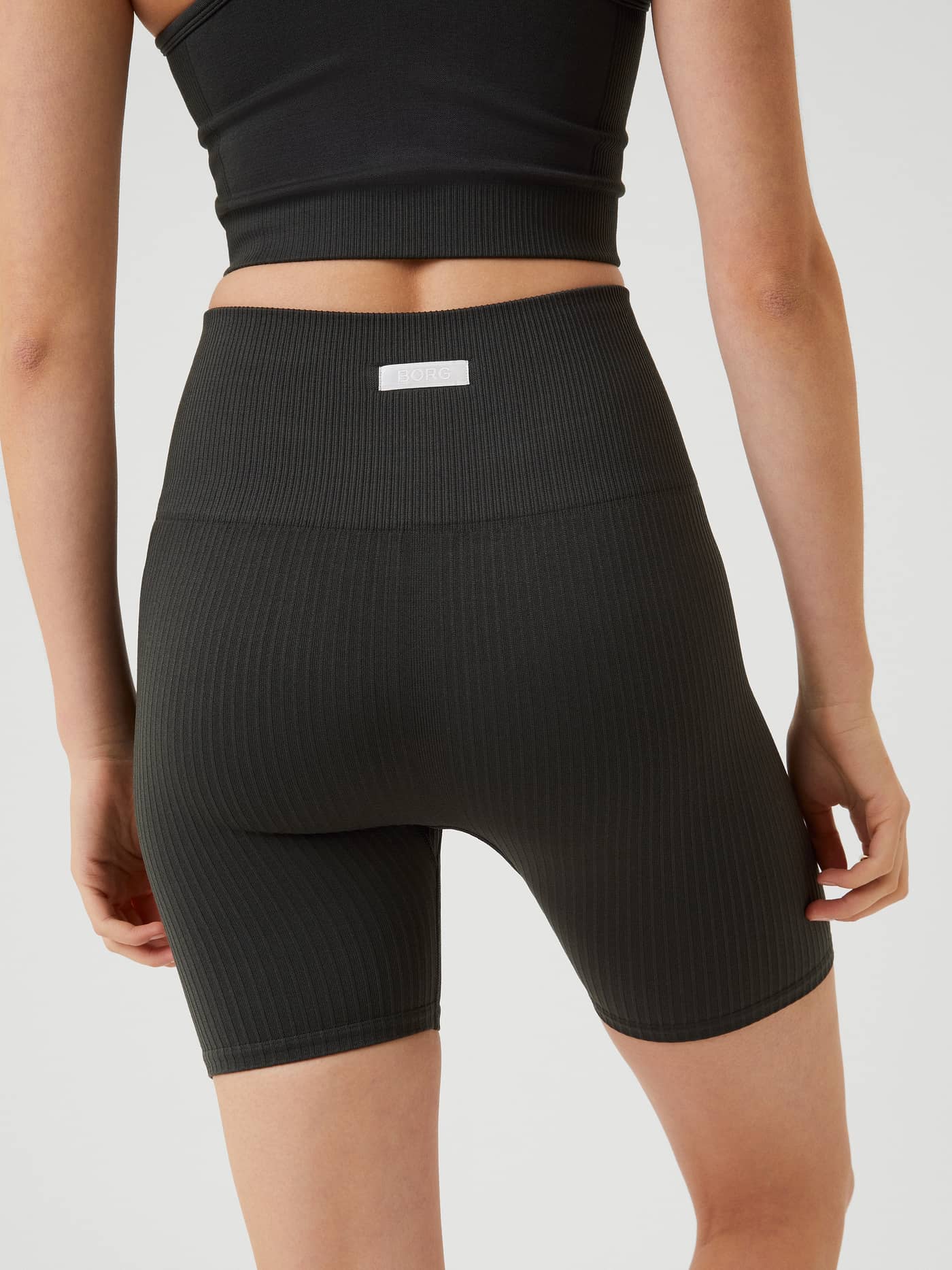 Studio Seamless Rib Shorts i Peat (Grön) sedda bakifrån med ribbad träningspassform och vit logotypetikett. - Image 3