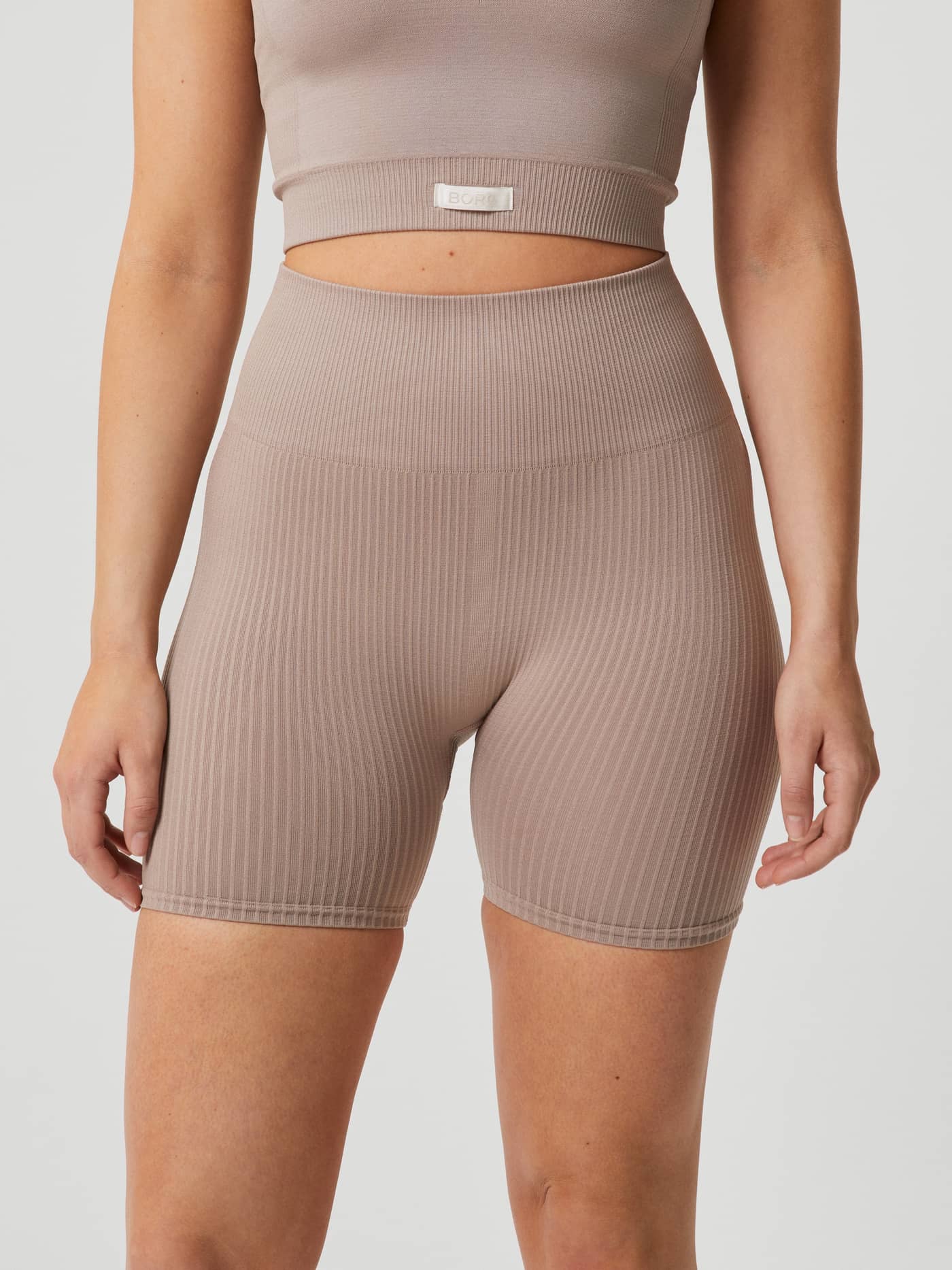 Front view of a model wearing Studio Seamless Rib Shorts in Etherea (Beige), with a slim ribbed fit for training. - Image 4