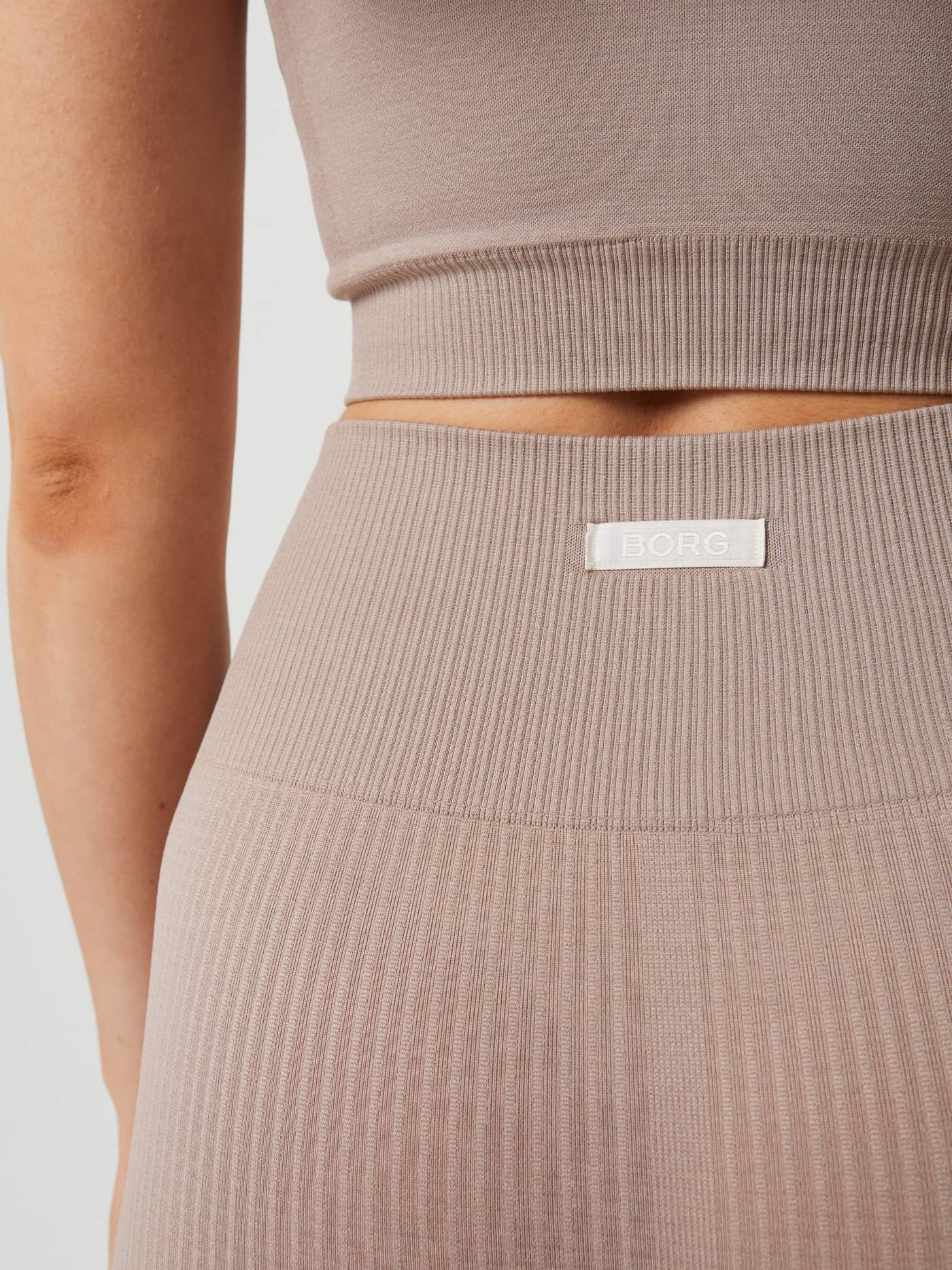 Close-up of the slim-fit Studio Seamless Rib Shorts in Etherea (Beige), showing rib-knitted training fabric and white logo. - Image 2