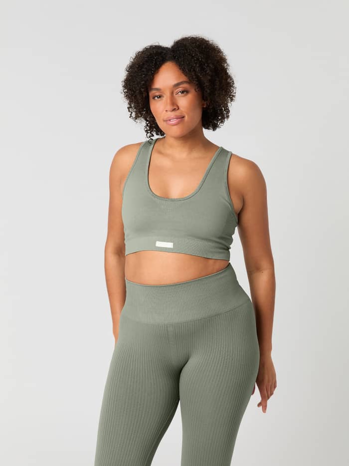 Front view of a woman wearing the high-waisted Studio Seamless Rib Tights in Vetiver (Green) with a ribbed training fit. - Image 3
