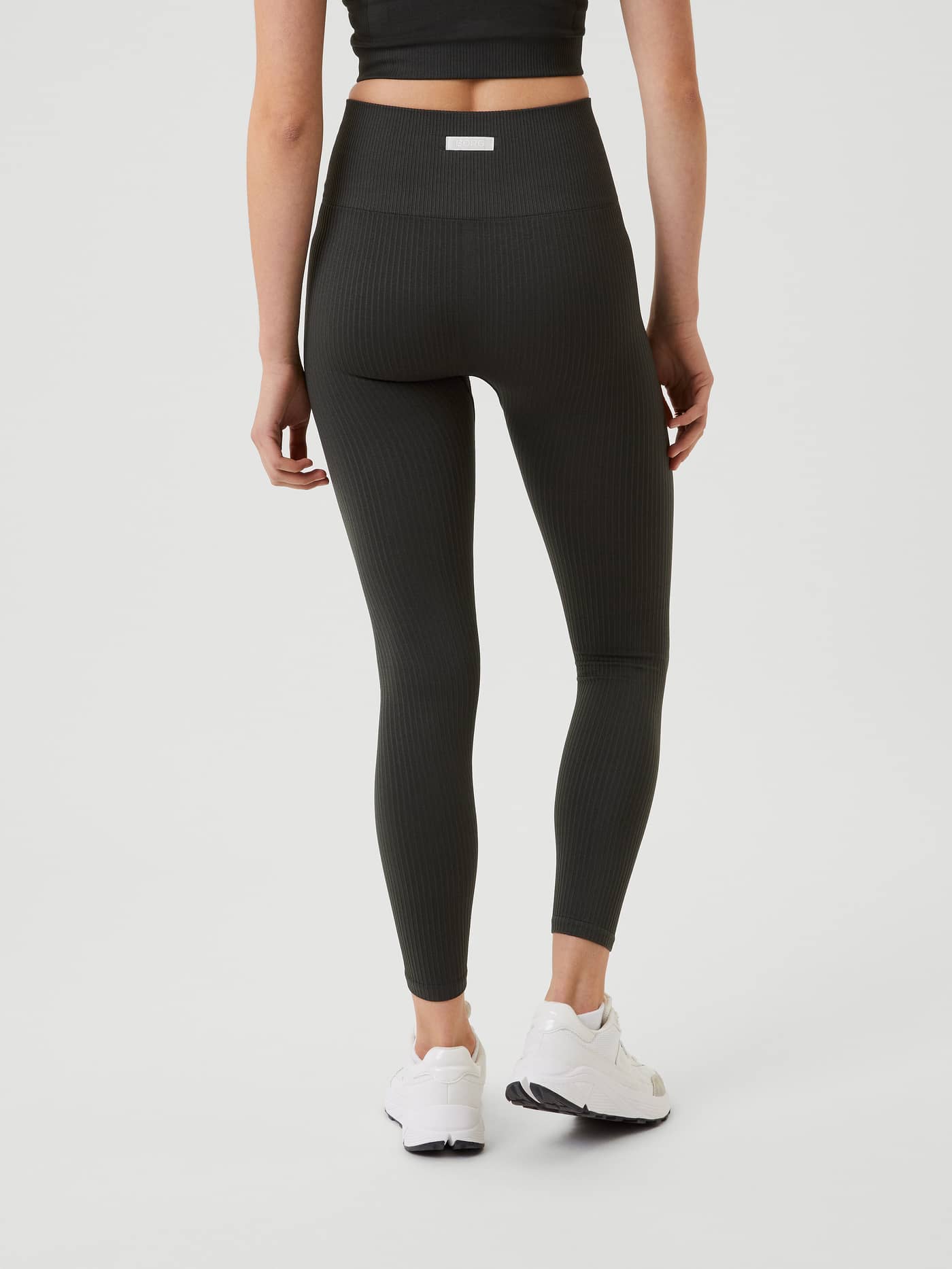 Back view of a model wearing the Björn Borg Studio Seamless Rib Tights in Peat (Green) featuring a white woven logo. - Image 3