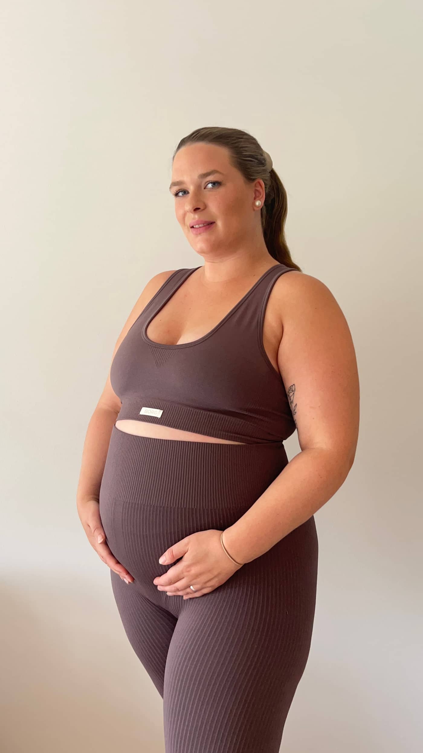 Three-quarter view of a pregnant model wearing the Studio Seamless Rib Tights in Sparrow (Brown) for a slim training fit. - Image 5