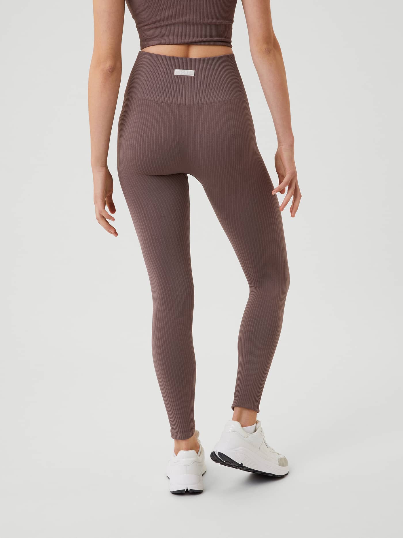 Back view of a model in Sparrow (Brown) Studio Seamless Rib Tights, featuring a high-waisted slim fit for training. - Image 3