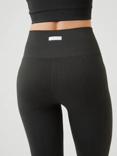 Back view of the Björn Borg Studio Seamless Rib Tights in Peat (Green), featuring a high-waisted fit and white logo label. - Image 4