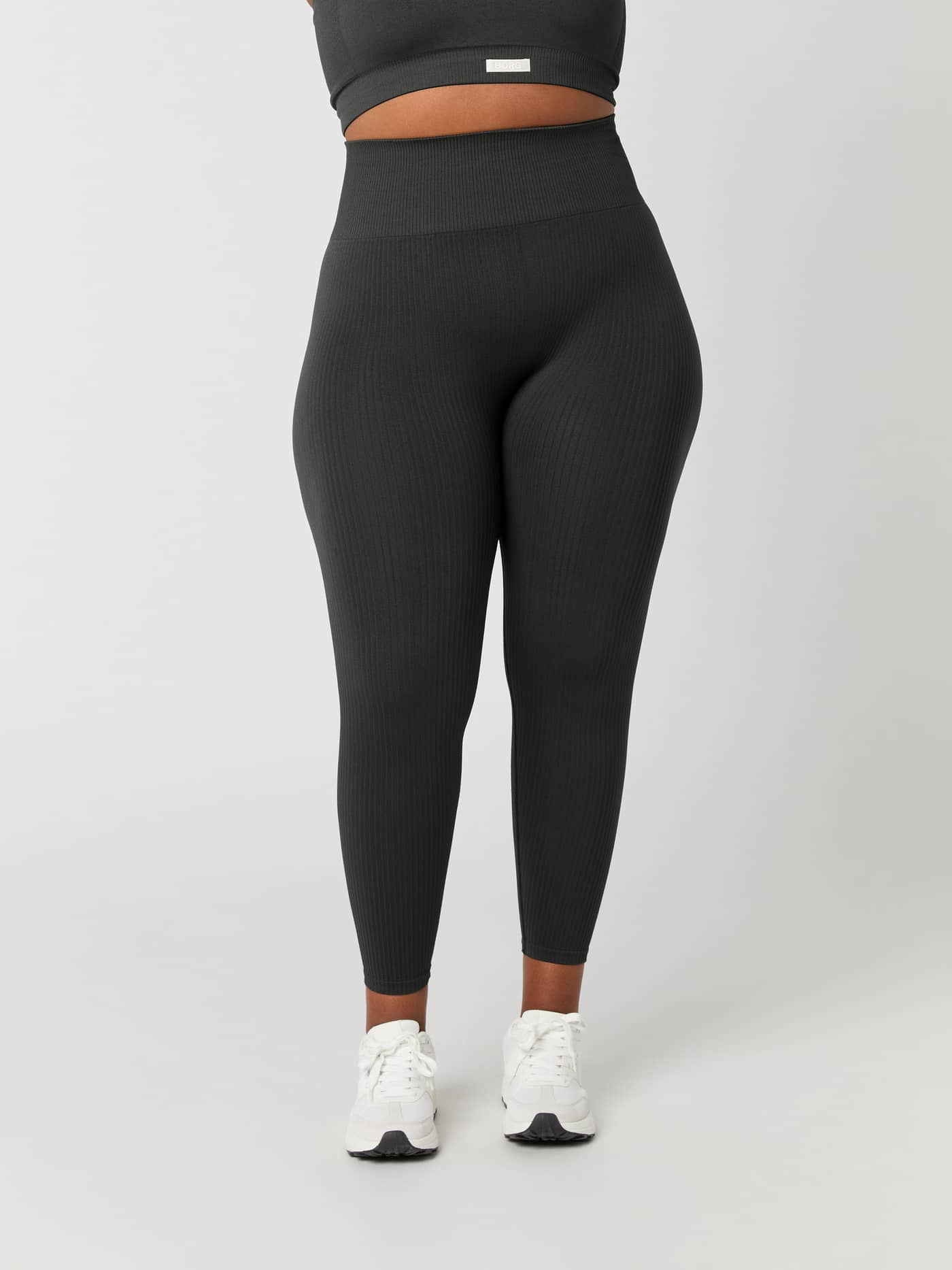 Front view of a model wearing the Studio Seamless Rib Tights in Peat (Green), featuring a high-waisted, slim training fit. - Image 7