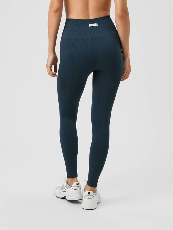 Back view of a model in the training Studio Seamless Rib Tights in Midnight Navy (Navy) with a white logo label. - Image 4