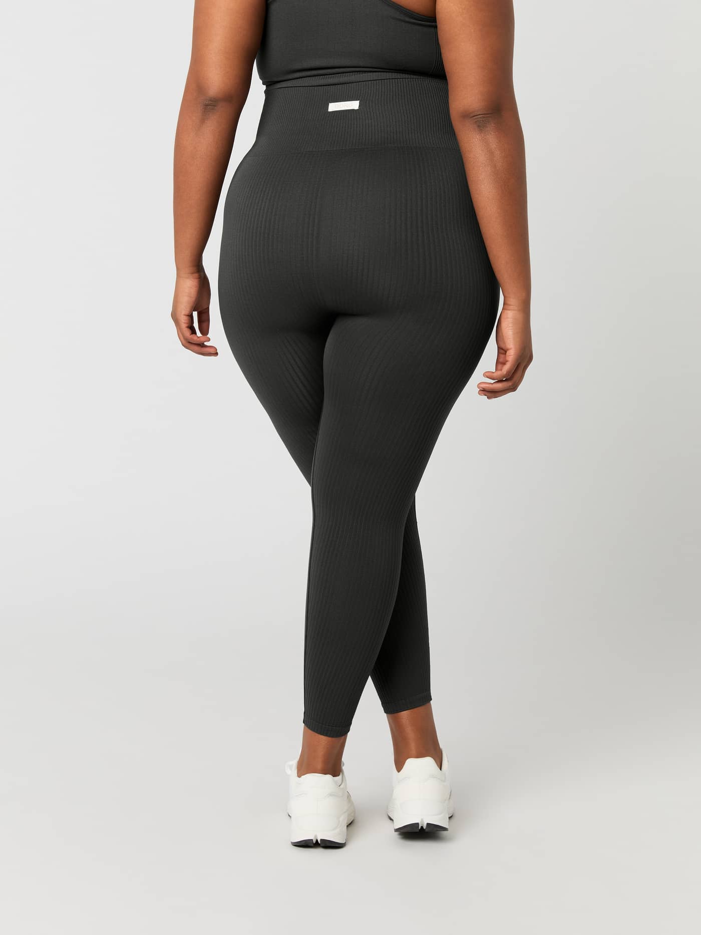 Back view of a model wearing high-waisted Björn Borg Studio Seamless Rib Tights in Peat (Green) for training and performance. - Image 8