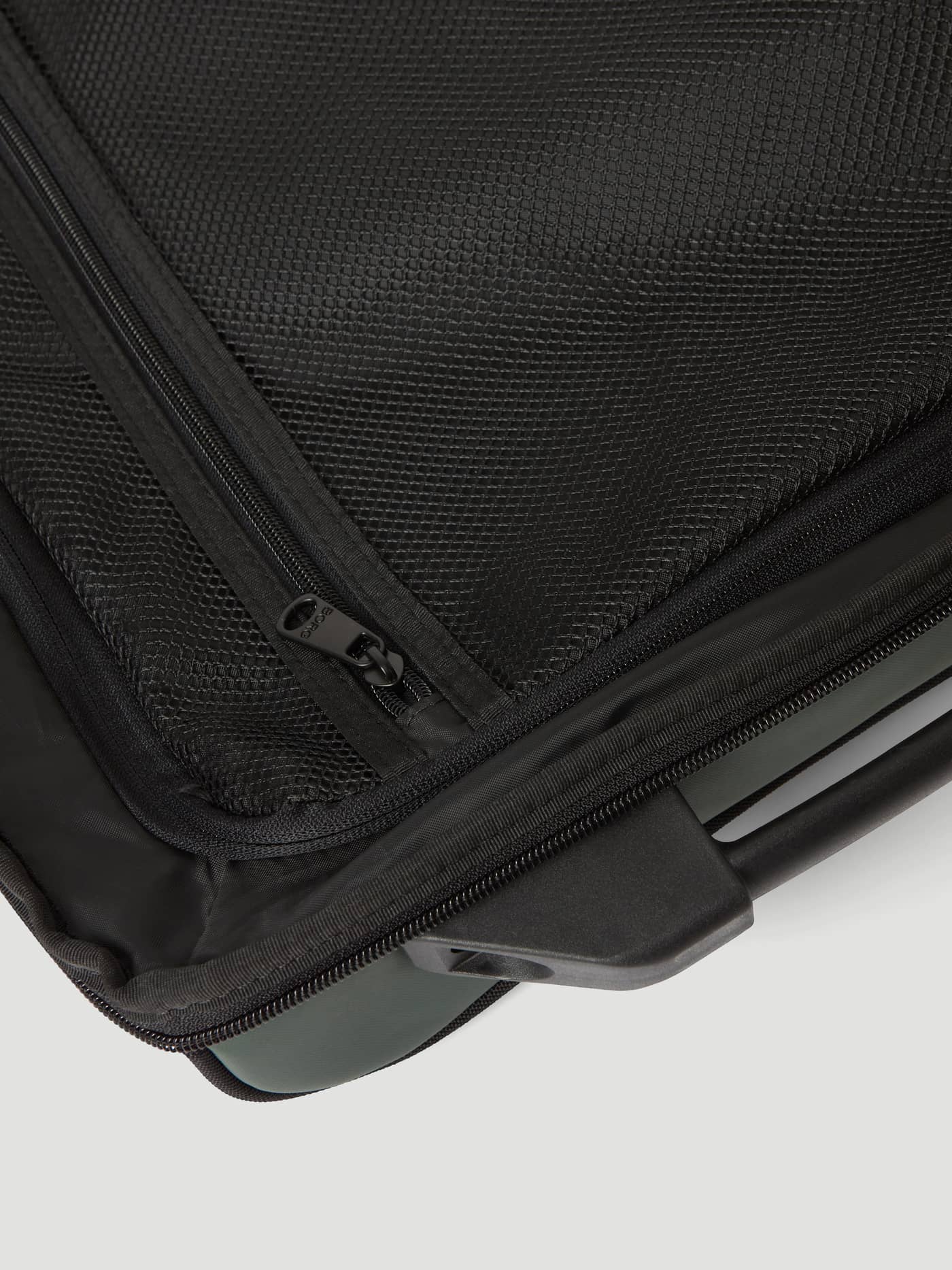 Close-up of the black mesh pocket and zipper on the Borg Travel Trolley S - 46L in Mountain View (Green). - Image 10