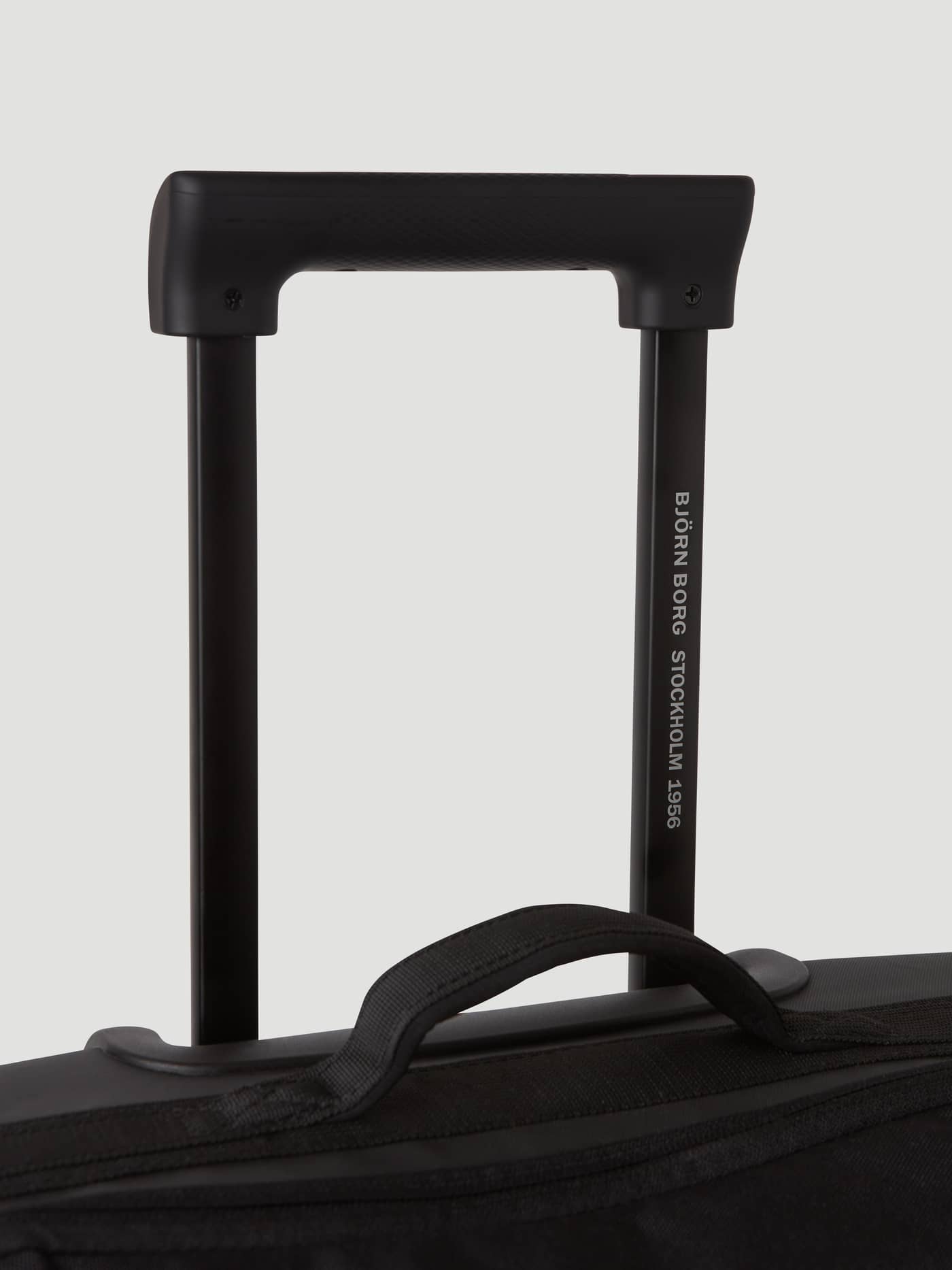 Close-up of the telescopic handle and strap on the Borg Travel Trolley L - 80L in Black Beauty (Black) with white logo. - Image 10
