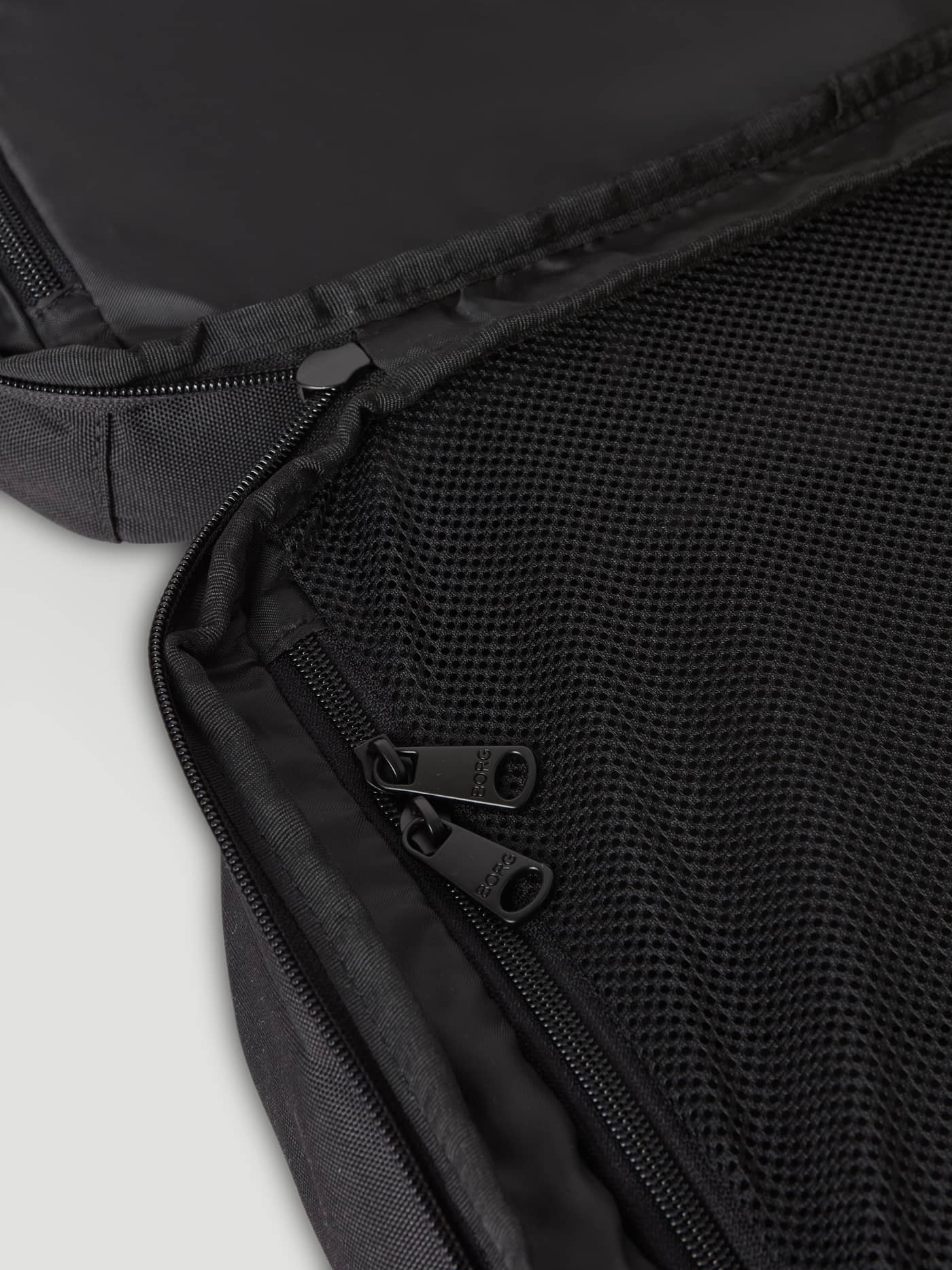 Interior view of the green Borg Travel Backpack L - 35L, featuring black mesh compartments and zippers with black logos. - Image 4