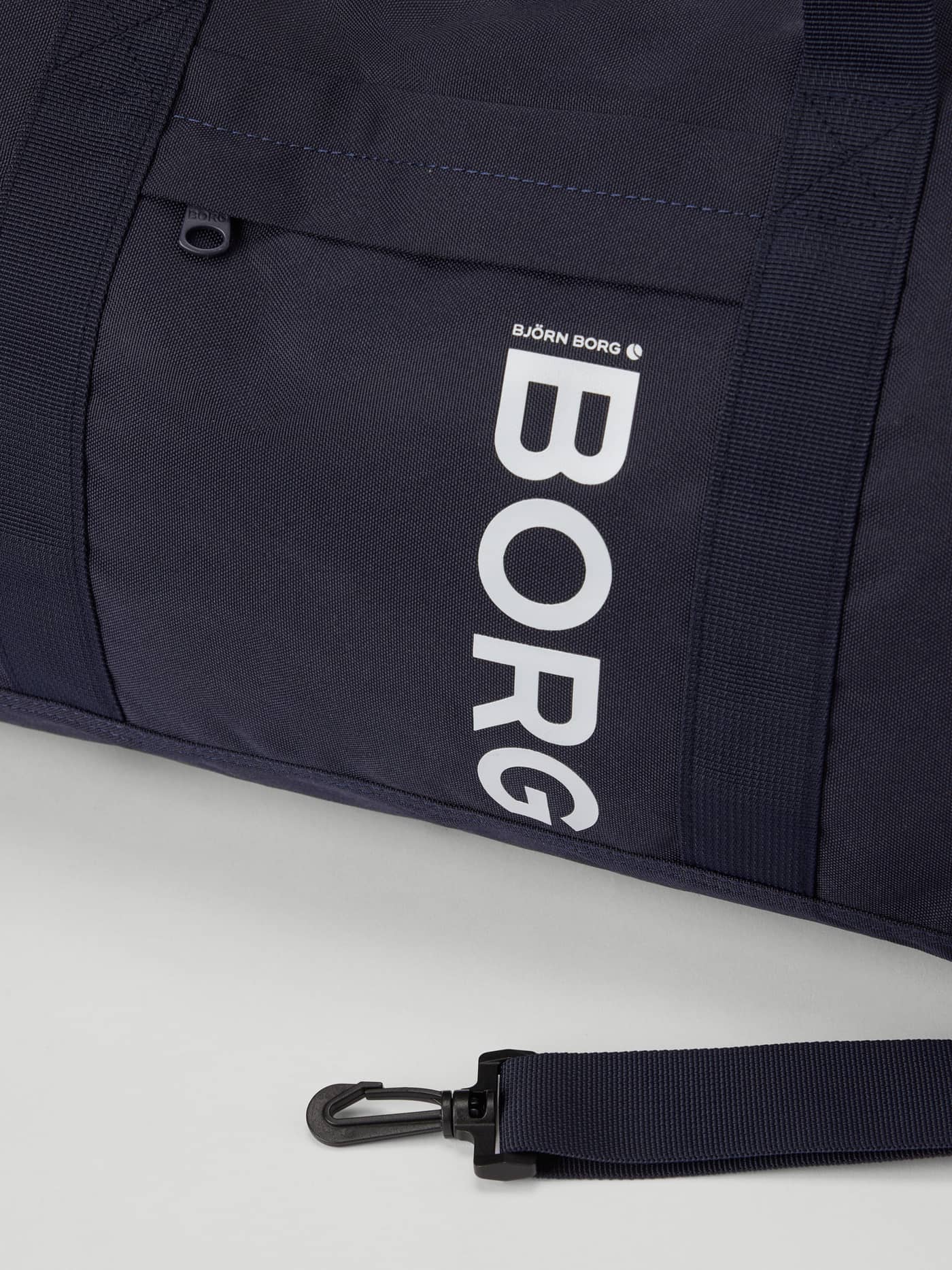 Detailed view of the Night Sky (Navy) Core Sports Bag 31L training bag featuring a white BORG logo and zippered pocket. - Image 3
