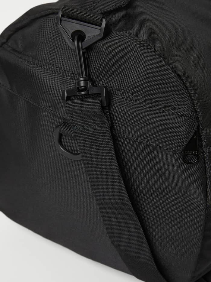 Närbild på axelrem och svart Borg-logotyp på Core Sports Bag 31L i Black Beauty (Svart) av återvunnen polyester för träning. - Image 3