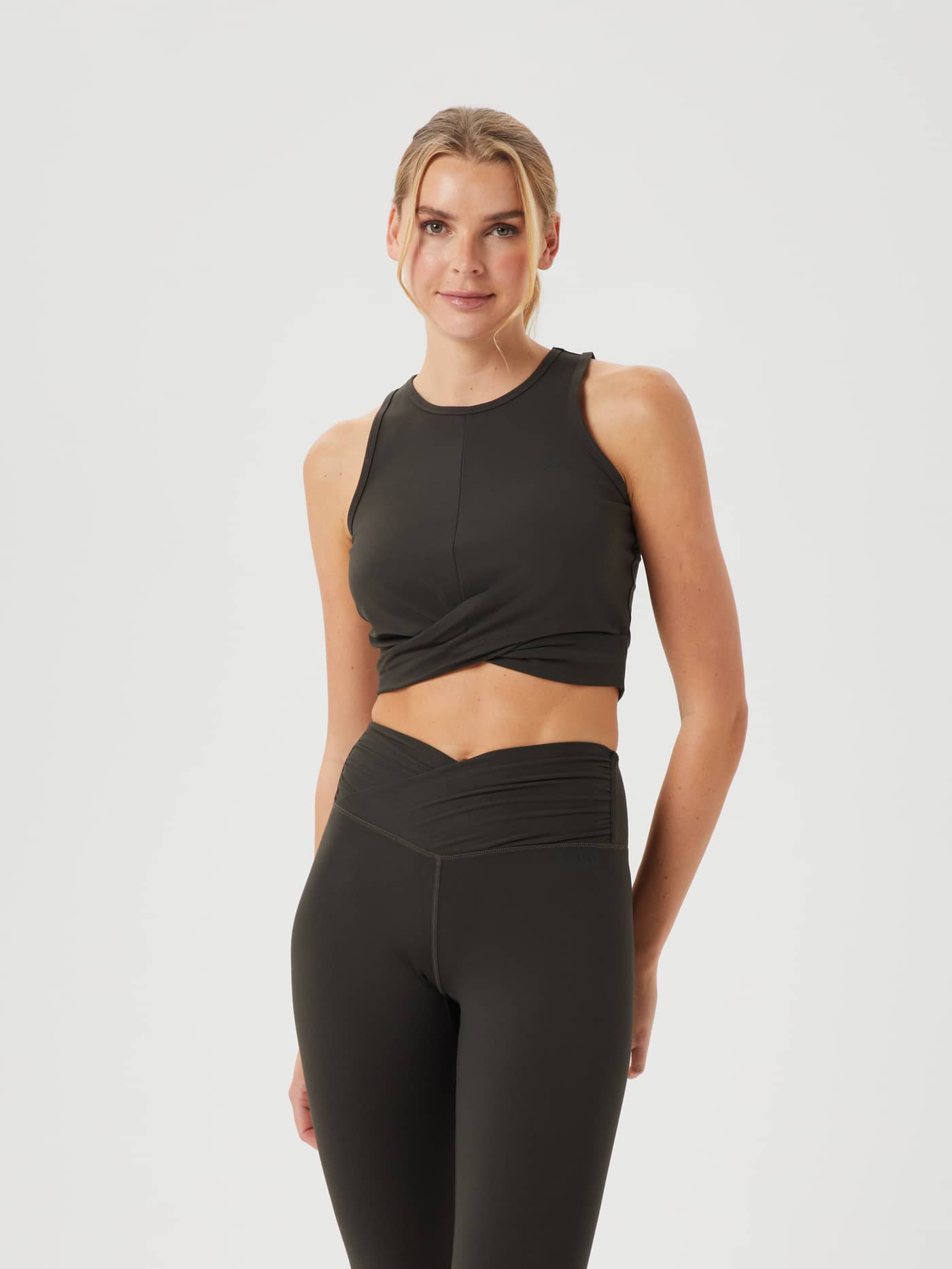 Front view of a model wearing Björn Borg Studio Cross Tank in Peat (Green), featuring a stylish twisted front for training. - Image 1