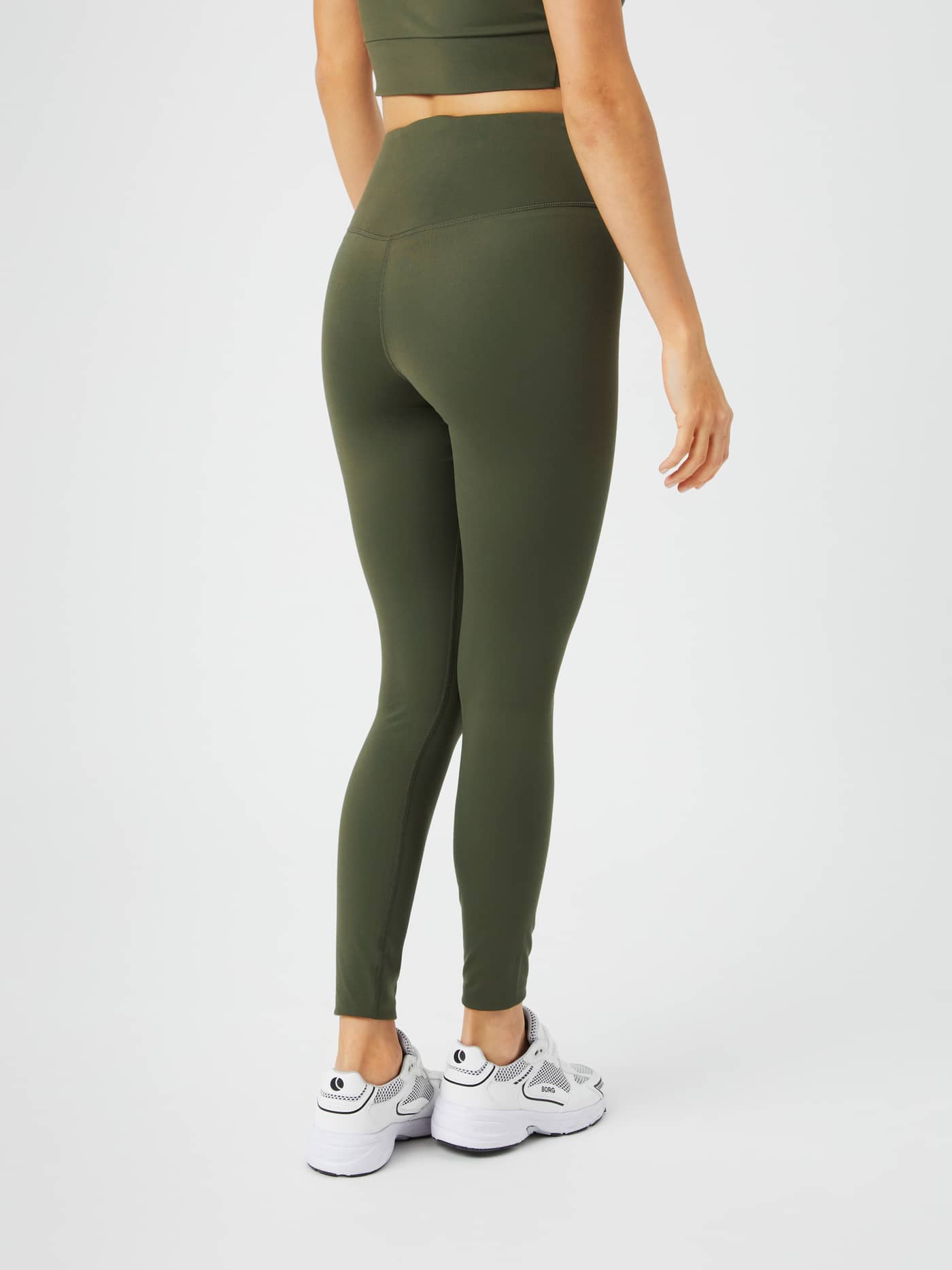 Back view of a woman wearing Studio Cross Tights in Olive Night (Green), in soft jersey for a supportive training fit. - Image 3
