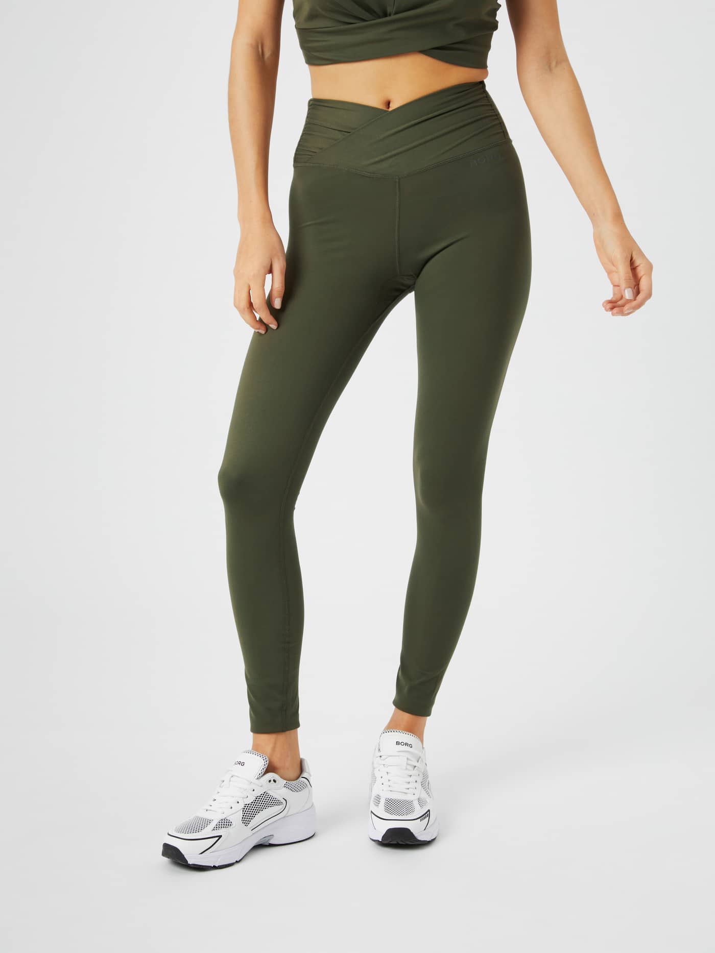 Front view of a woman in Björn Borg Studio Cross Tights in Olive Night (Green) with a twisted waist for training. - Image 2