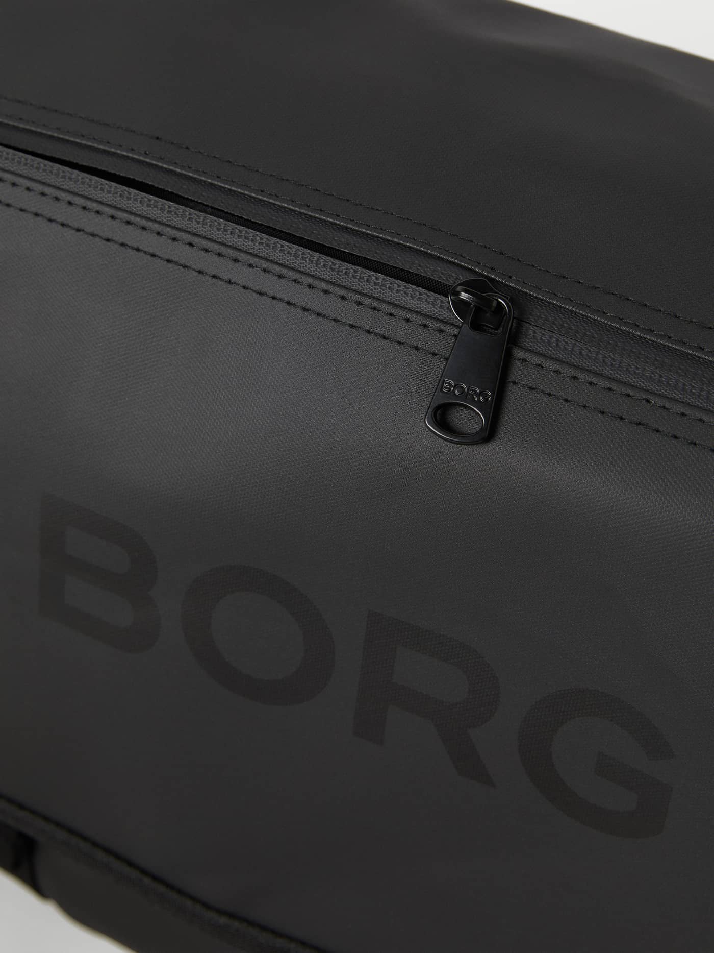 Ton-sur-ton zwart logo en ritsdetail op de rubberachtige Black Beauty (Zwart) Borg Duffle Messenger Bag 12L. - Image 6