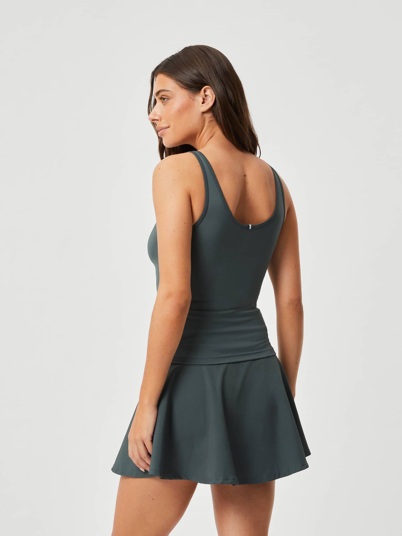 Side-back view of a model wearing the slim-fit Björn Borg Ace Deep V Tank in Urban Chic (Green) for tennis. - Image 2