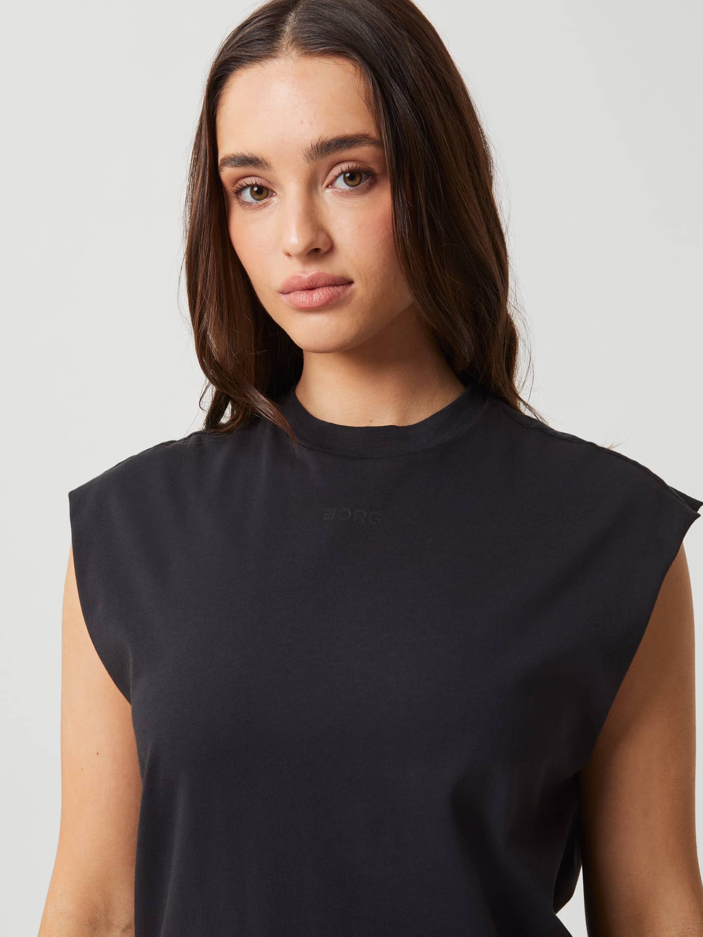 Studio Loose Fit Tank in Black Beauty (Zwart) voor training met een ton-sur-ton logo op de borst in close-up. - Image 4