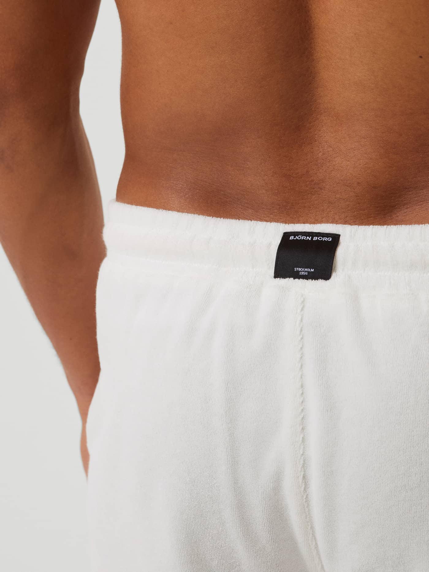 Back view of a man wearing the Björn Borg Toweling Pool Shorts in Egret (White), showing the black logo on soft fabric. - Image 4