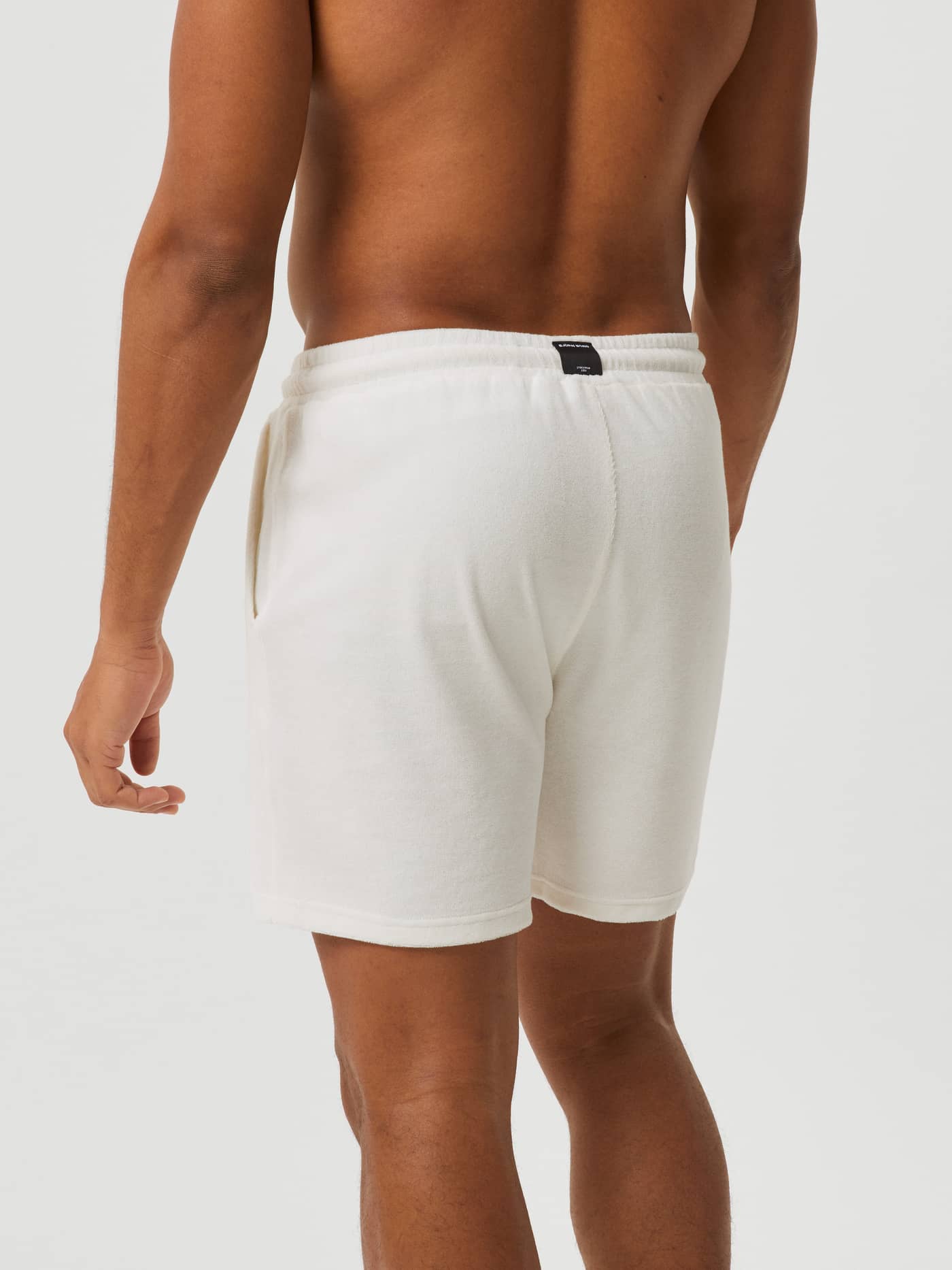 Back view of a man wearing the Borg Toweling Pool Shorts in Egret (White), featuring a regular fit and black logo label. - Image 3