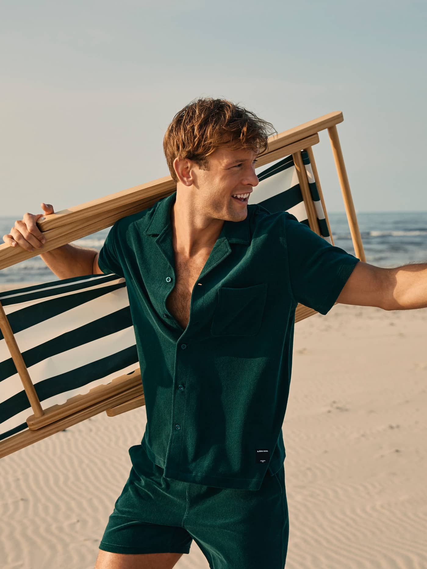 Grønn Borg Toweling Pool Shorts og skjorte i frotté på en mann sett fra siden på stranden, stilfull og funksjonell. - Image 1