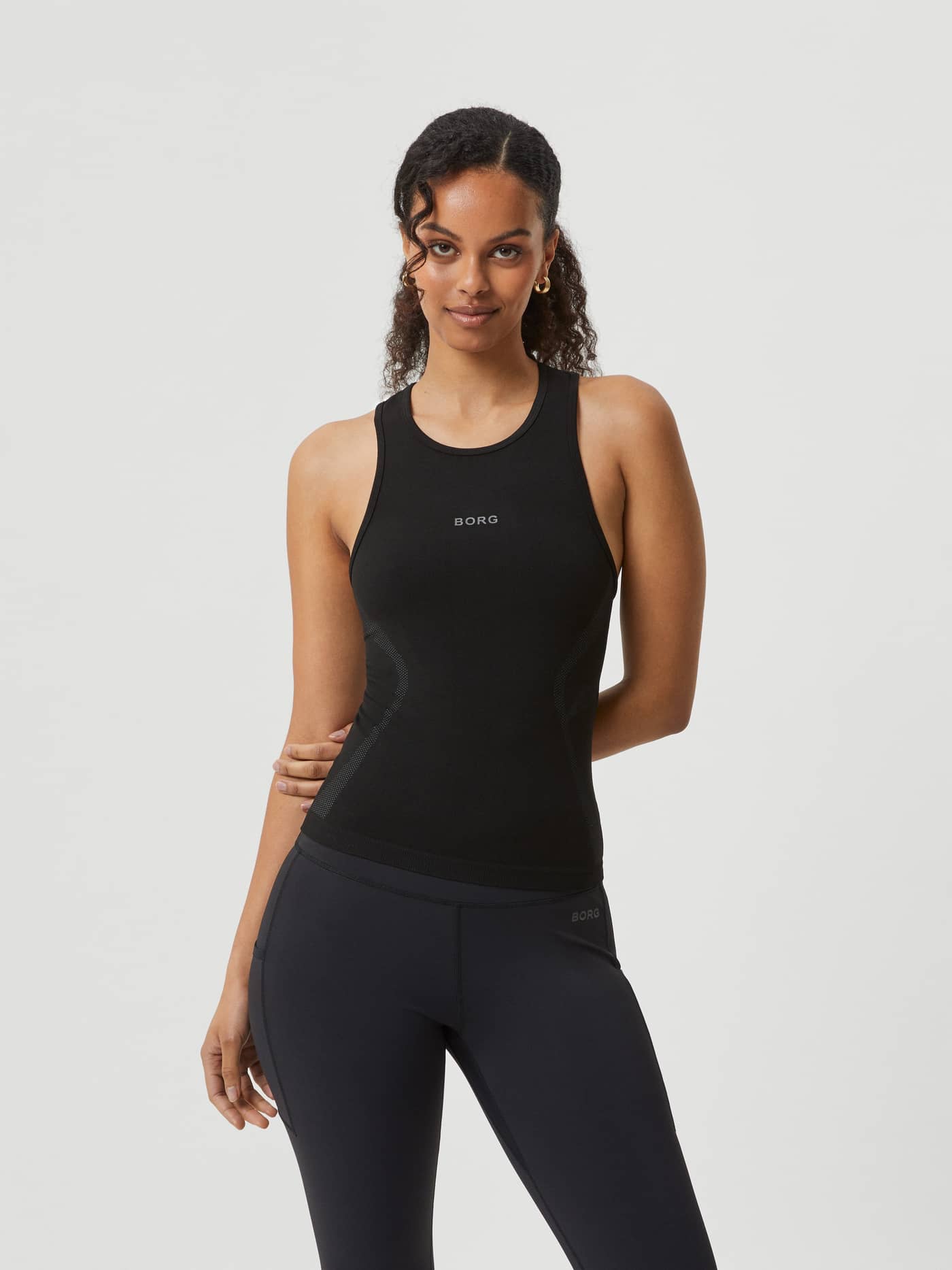 Front view of a model in the Borg Running Seamless Tank in Black Beauty (Black) with a grey logo for a seamless running fit. - Image 1