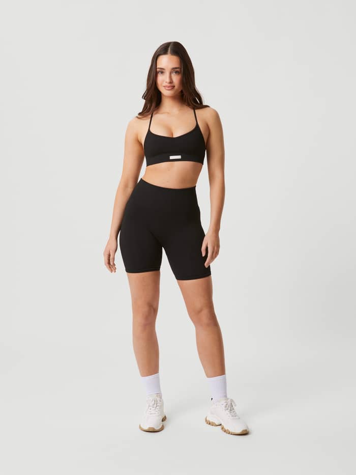 Ganzkörper-Vorderansicht einer Frau im Studio Seamless Ribbed Strap Bra in Schwarz aus nahtlosem Rippstrick für Training. - Image 3