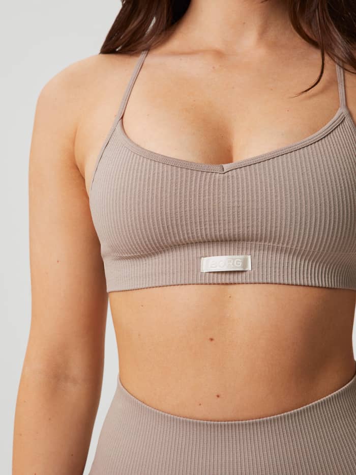 Nahaufnahme des Studio Seamless Ribbed Strap Bra in Etherea (Beige) mit weißem gewebtem Logo und stilvoller Passform. - Image 3