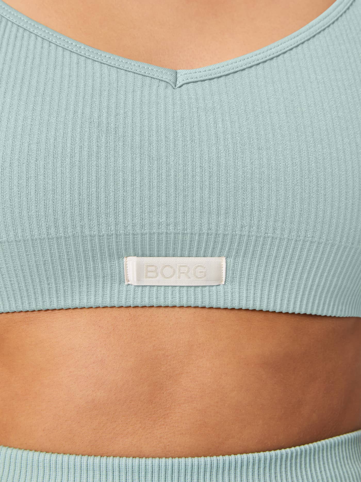 Close-up of the women's Studio Seamless Ribbed Strap Bra in Blue, featuring a ribbed fit and woven BORG logo label. - Image 4