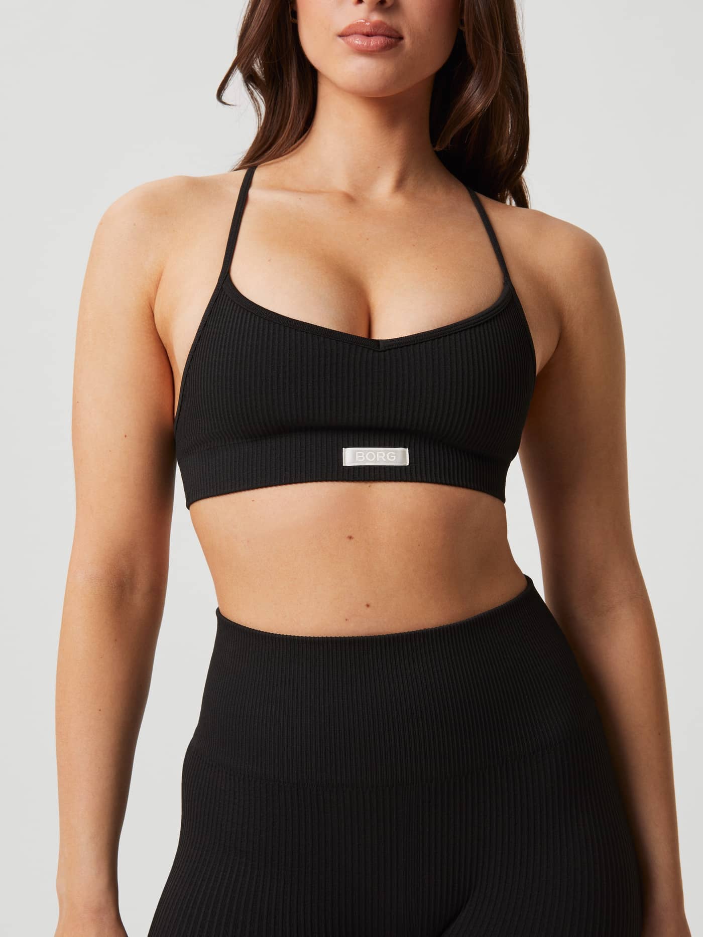 Studio Seamless Ribbed Strap Bra in Black Beauty (Zwart) voor training, getoond in vooraanzicht met een wit logolabel. - Image 6