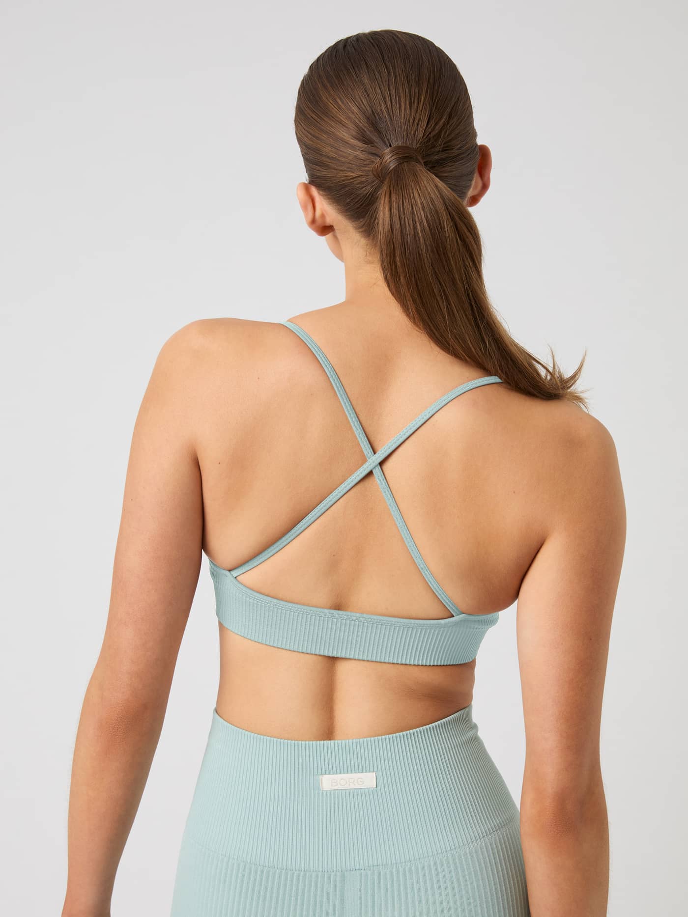 Back view of the rib-knitted Studio Seamless Ribbed Strap Bra in Gray Mist (blue) featuring thin crossover straps. - Image 5