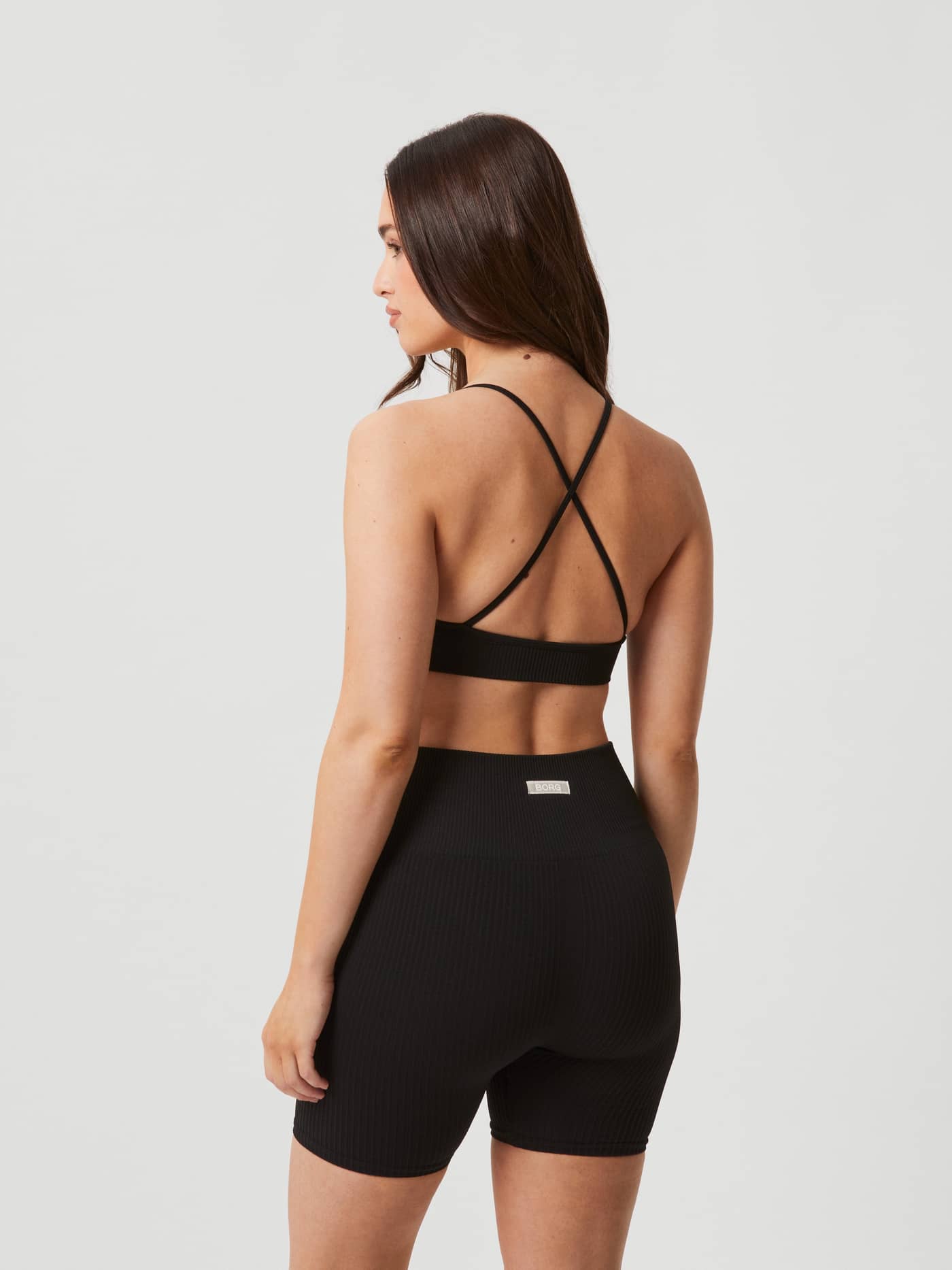 Studio Seamless Ribbed Strap Bra in Black Beauty (Zwart) met gekruiste bandjes voor training, getoond in achteraanzicht. - Image 2