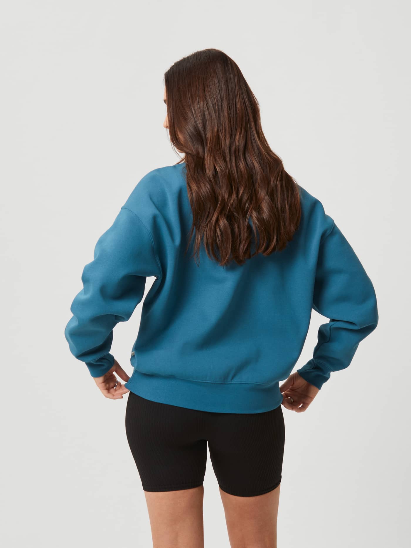 Back view of a woman wearing the Björn Borg Studio Oversized Crew in Mallard Blue (Blue) with a relaxed, oversized fit. - Image 3