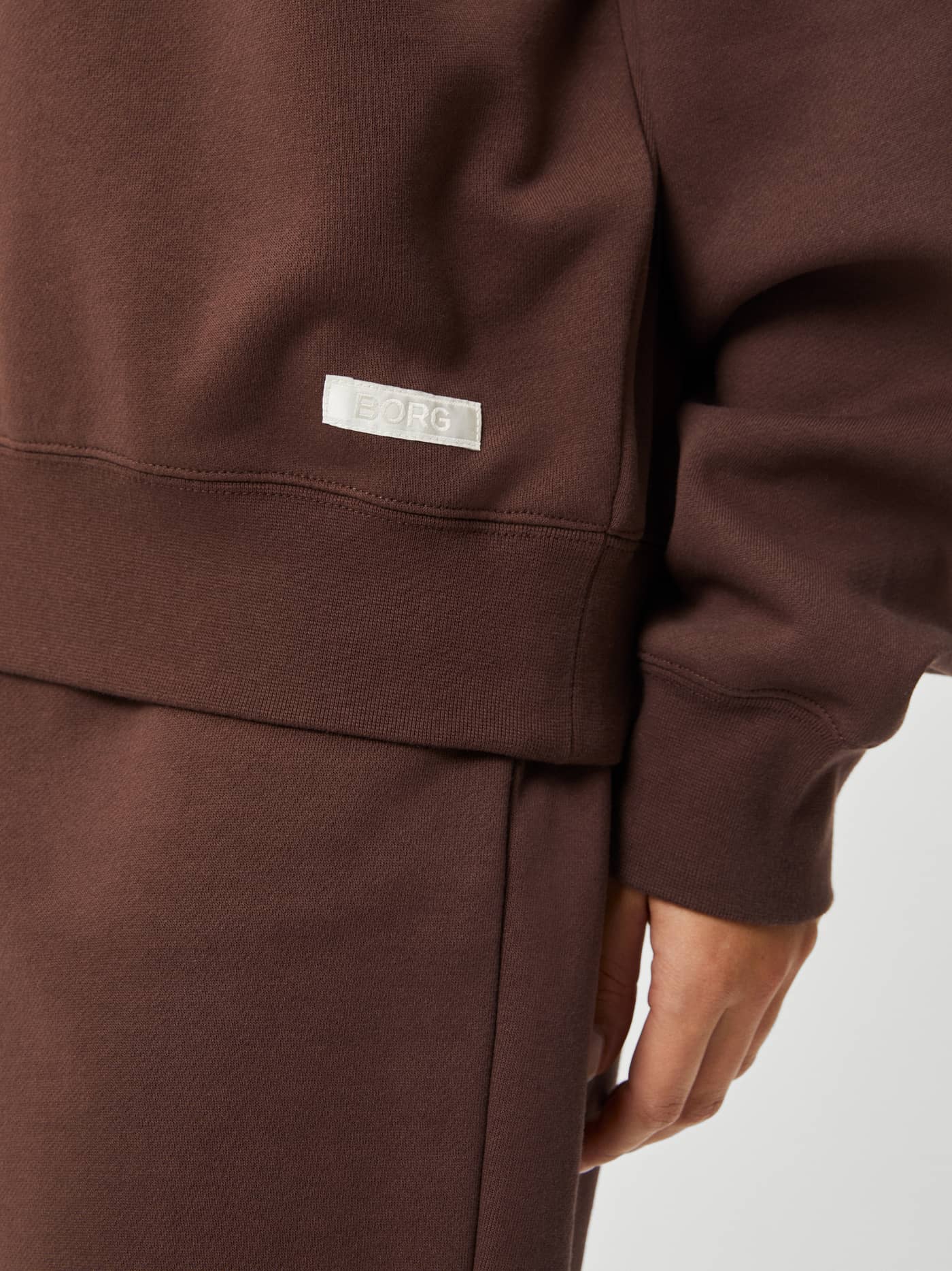 Detailed close-up of the women's Studio Oversized Crew in French Toast (Brown) with a side-placed white Borg logo label. - Image 6