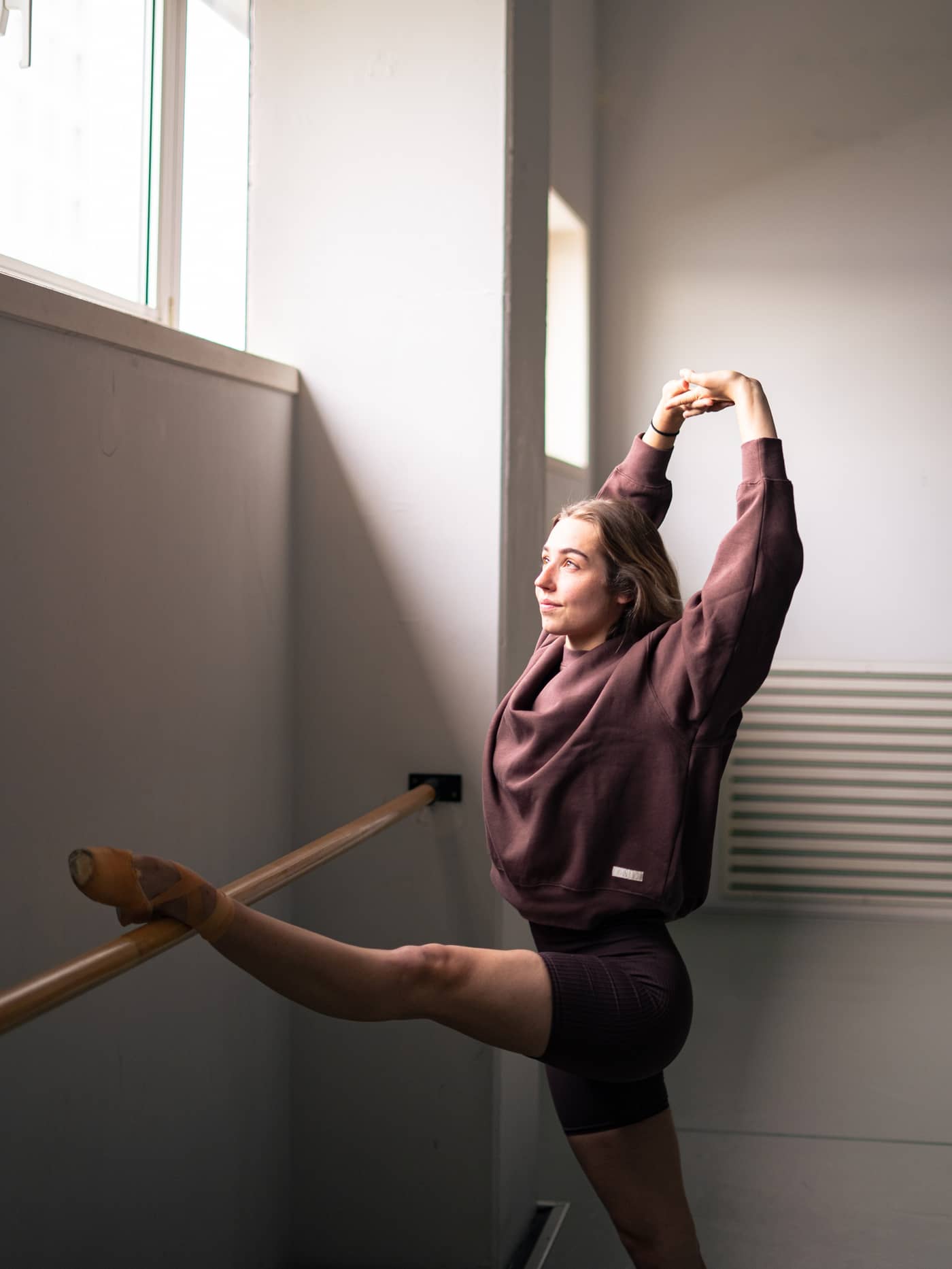 Björn Borg Studio Oversized Crew in French Toast (Brown) in cotton, worn by a woman stretching for a stylish, relaxed fit. - Image 2