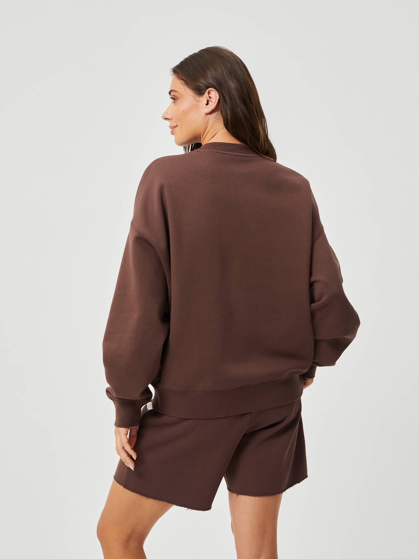 Back view of a woman wearing the Björn Borg Studio Oversized Crew in French Toast (Brown) made of soft cotton, relaxed fit. - Image 5
