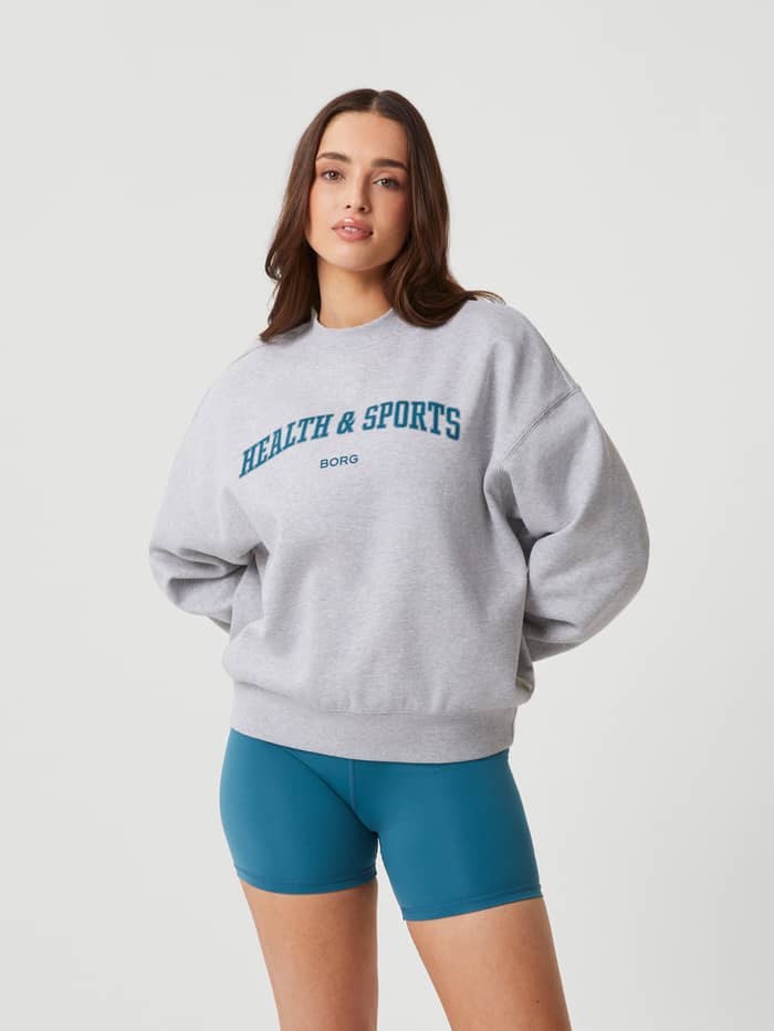 Vorderansicht einer Frau im Studio Oversized Crew in Light Grey Melange (Grau) mit Health & Sports-Print. - Image 2