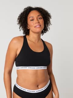 Vista frontal de una modelo con el Core Logo Soft Top 1-pack en Negro, elástico de logo blanco y diseño de espalda nadadora. - Image 3