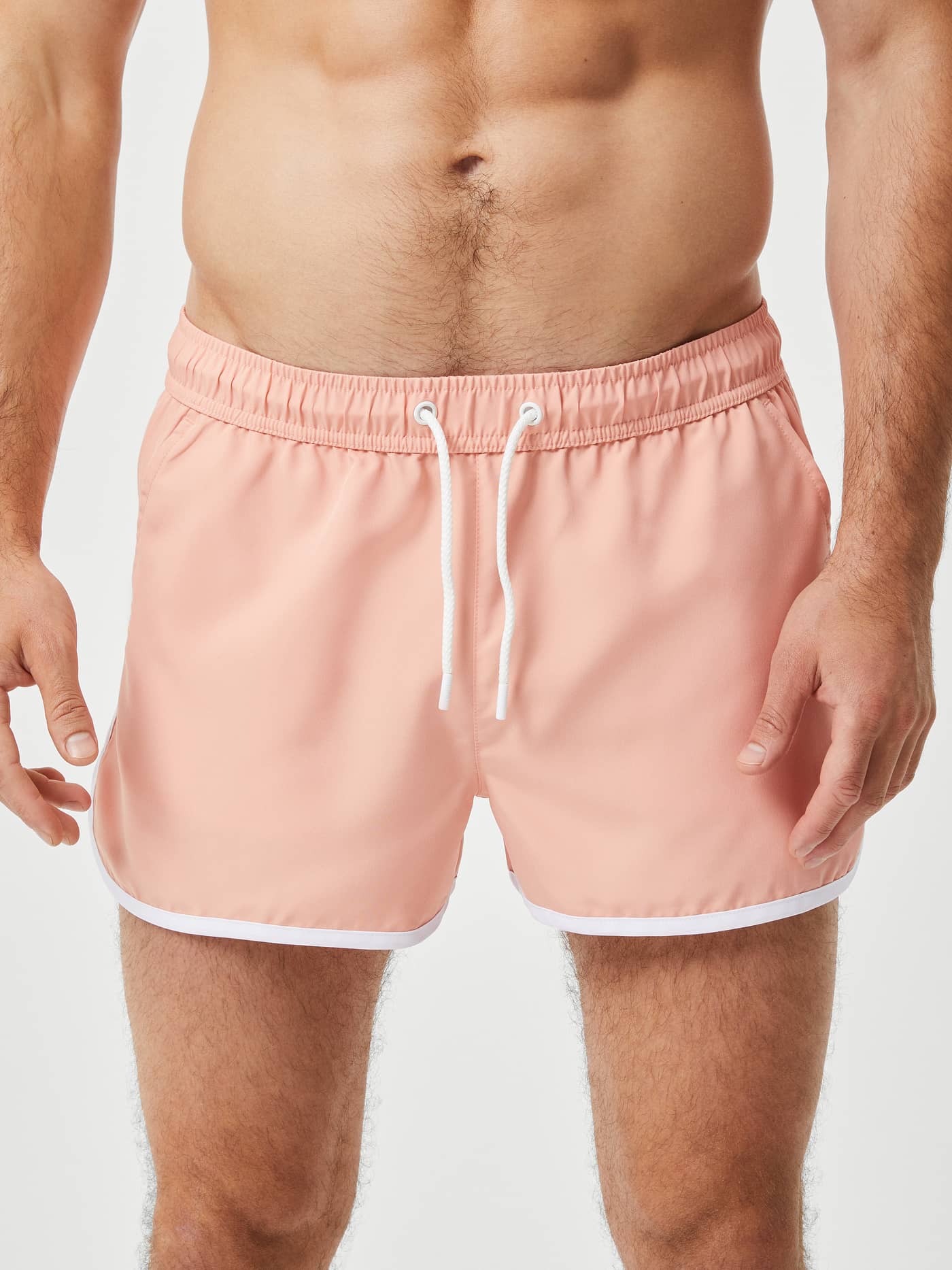 Vorderansicht eines Mannes in Borg Retro Swim Shorts in Coral Almond (Rosa) mit schmaler Passform und weißen Retro-Paspeln. - Image 2