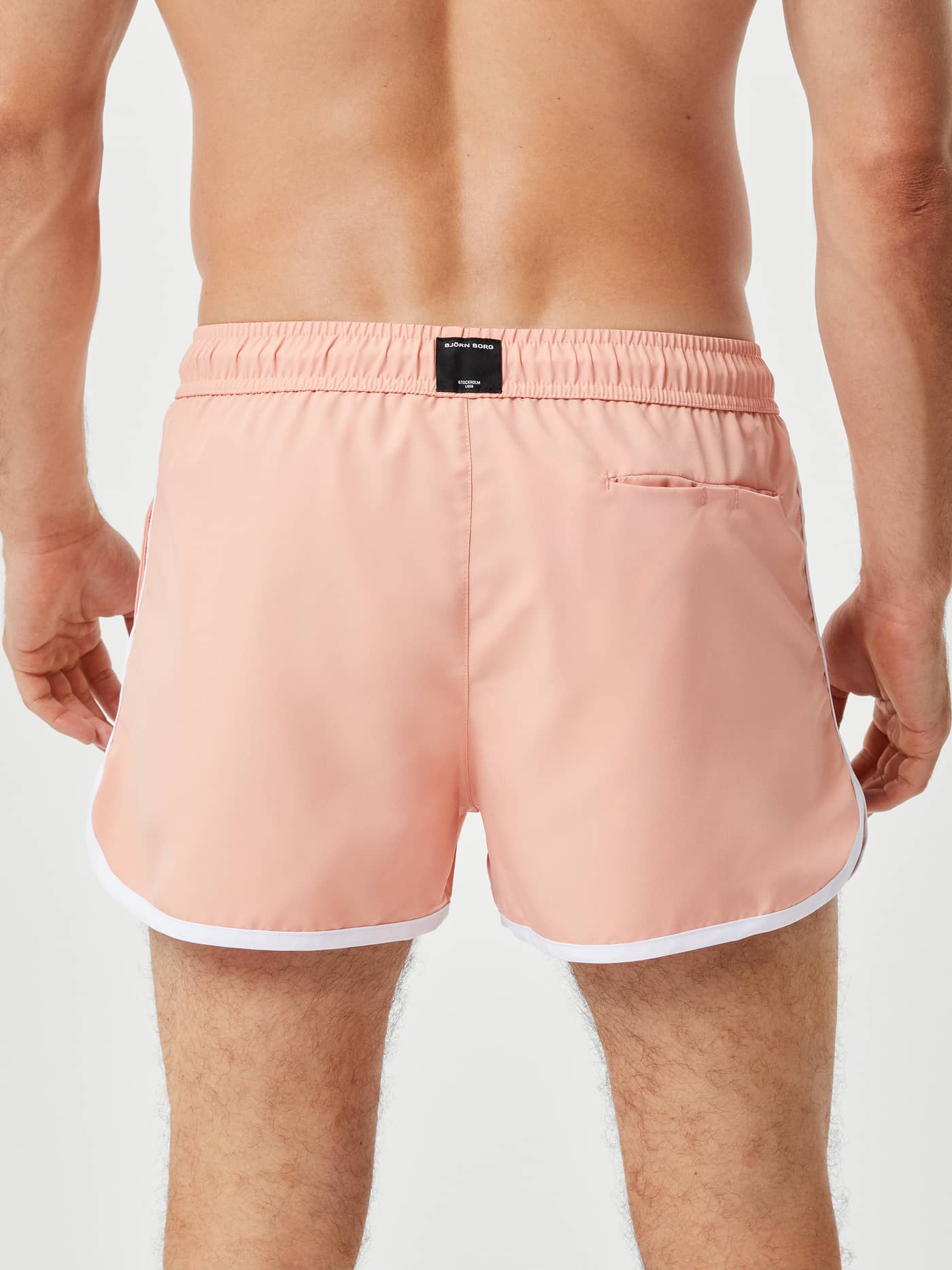Rückansicht der Borg Retro Swim Shorts in Coral Almond (Rosa) mit weißem Saum und schwarzem Logo-Label. - Image 3