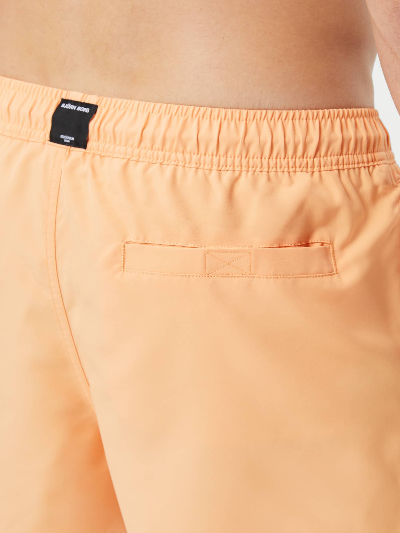 Detailed back view of the Borg Solid Swim Shorts in Orange Chiffon (orange), featuring the Velcro pocket and logo label. - Image 4
