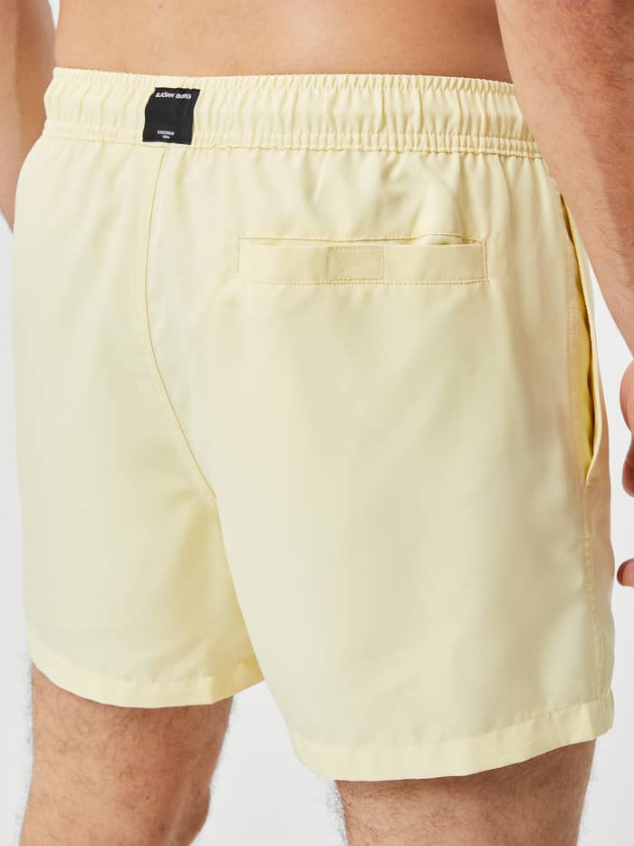 Close-up achteraanzicht van de Borg Solid Swim Shorts in French Vanilla (Geel) met een klittenbandzak en zwart logo. - Image 4