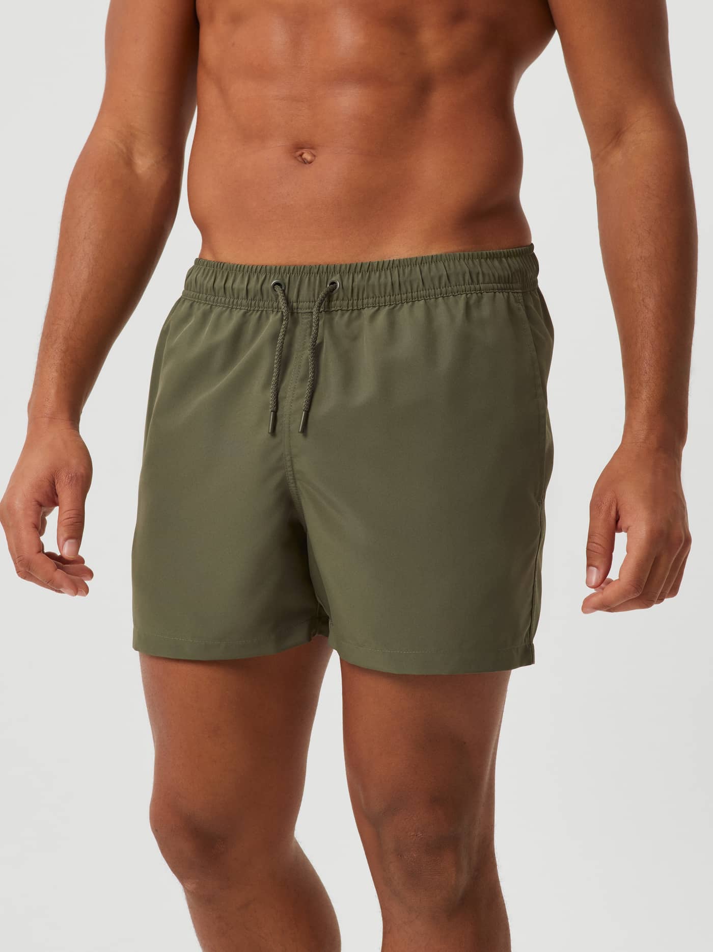 Vista frontal de un hombre con los Borg Solid Swim Shorts de corte holgado en Beetle (Verde) fabricados en poliéster. - Image 2