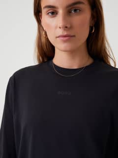 Front close-up of a woman wearing the Studio Oversized T-Shirt in Black Beauty (Black) with a tonal BORG logo. - Image 7