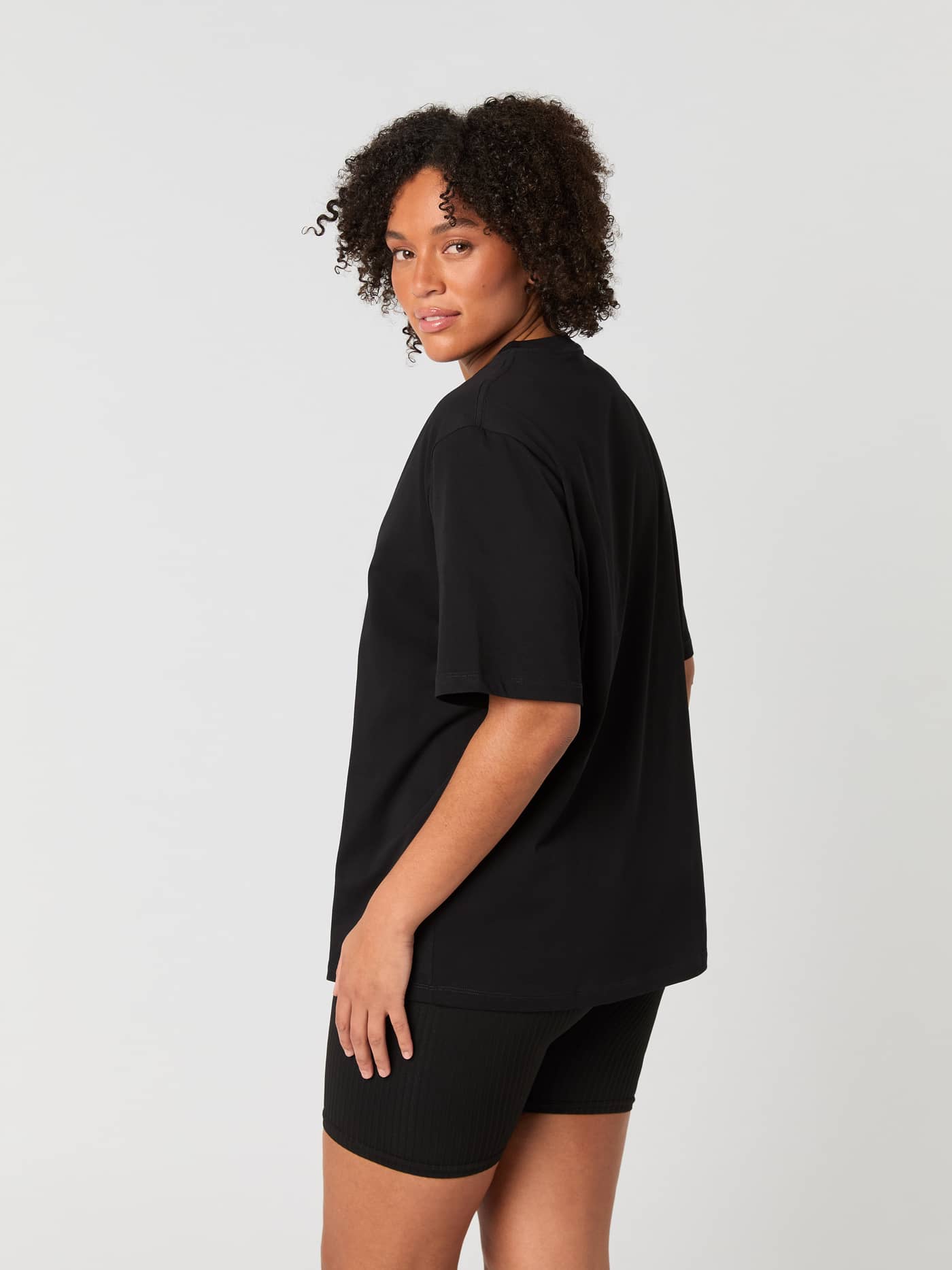 Side view of a model wearing the Björn Borg Studio Oversized T-Shirt in Black Beauty (Black) with a relaxed fit. - Image 2